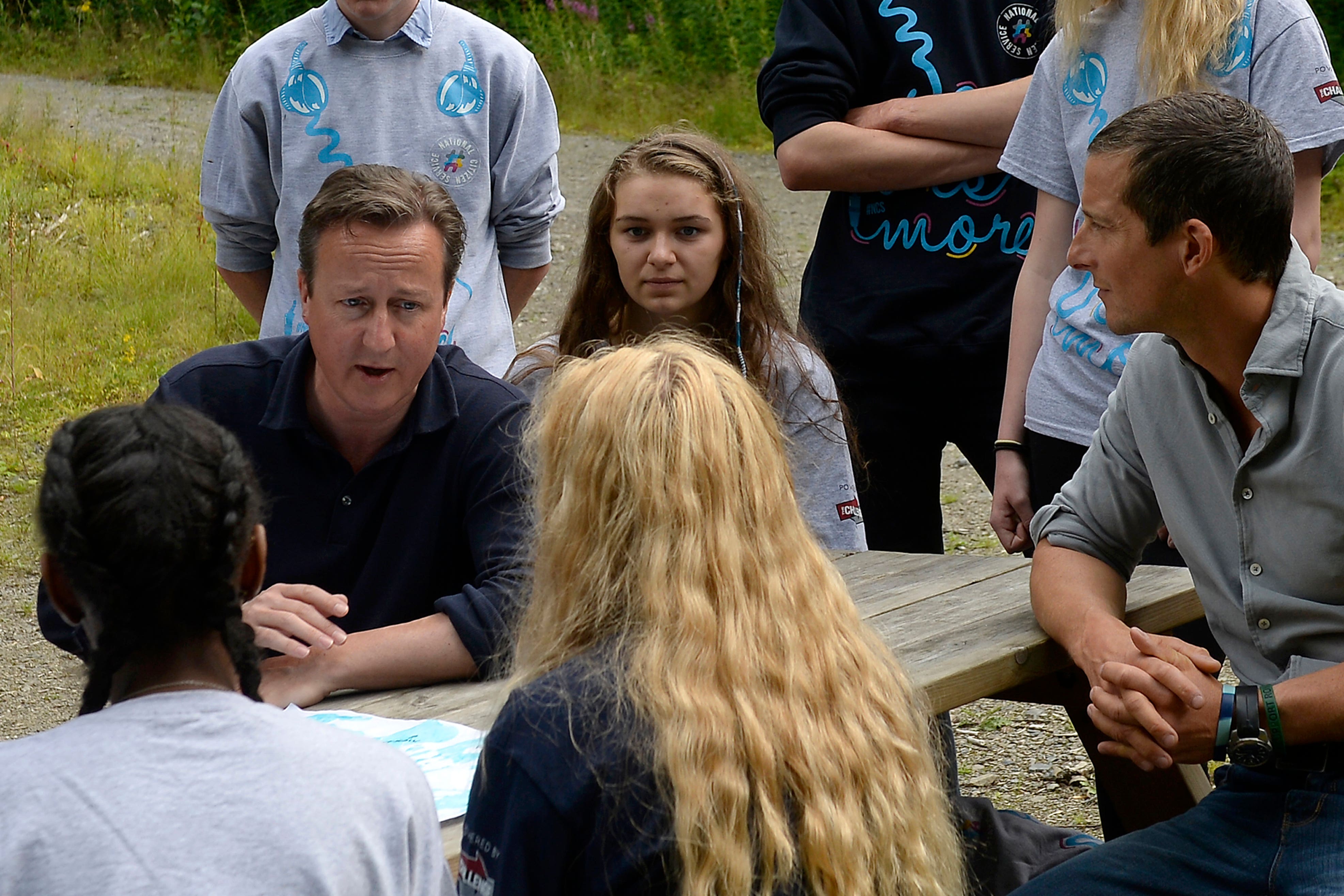 Then prime minister David Cameron (left) and survival expert Bear Grylls (right) talking to members of the National Citizen Service during a visit to Oaklands Outdoor Education Centre in Snowdonia in August 2015 (Joe Giddens/PA)