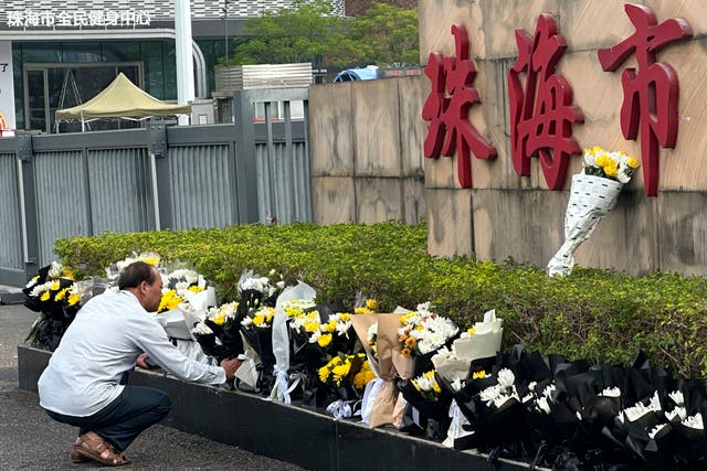 <p>A man offers flowers outside the Zhuhai People's Fitness Plaza where a man rammed his car into people exercising at the sports center</p>