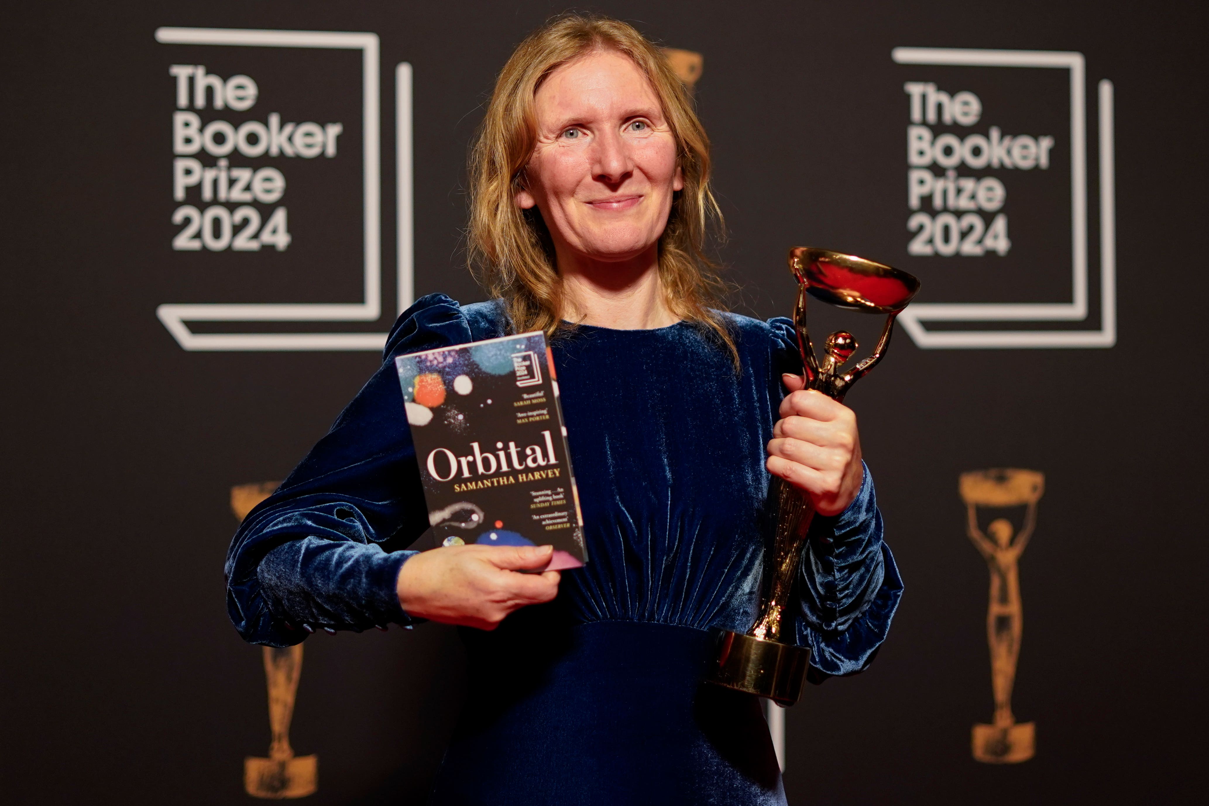 Samantha Harvey poses with the trophy and her book Orbital after winning the 2024 Booker Prize. (AP Photo/Alberto Pezzali)