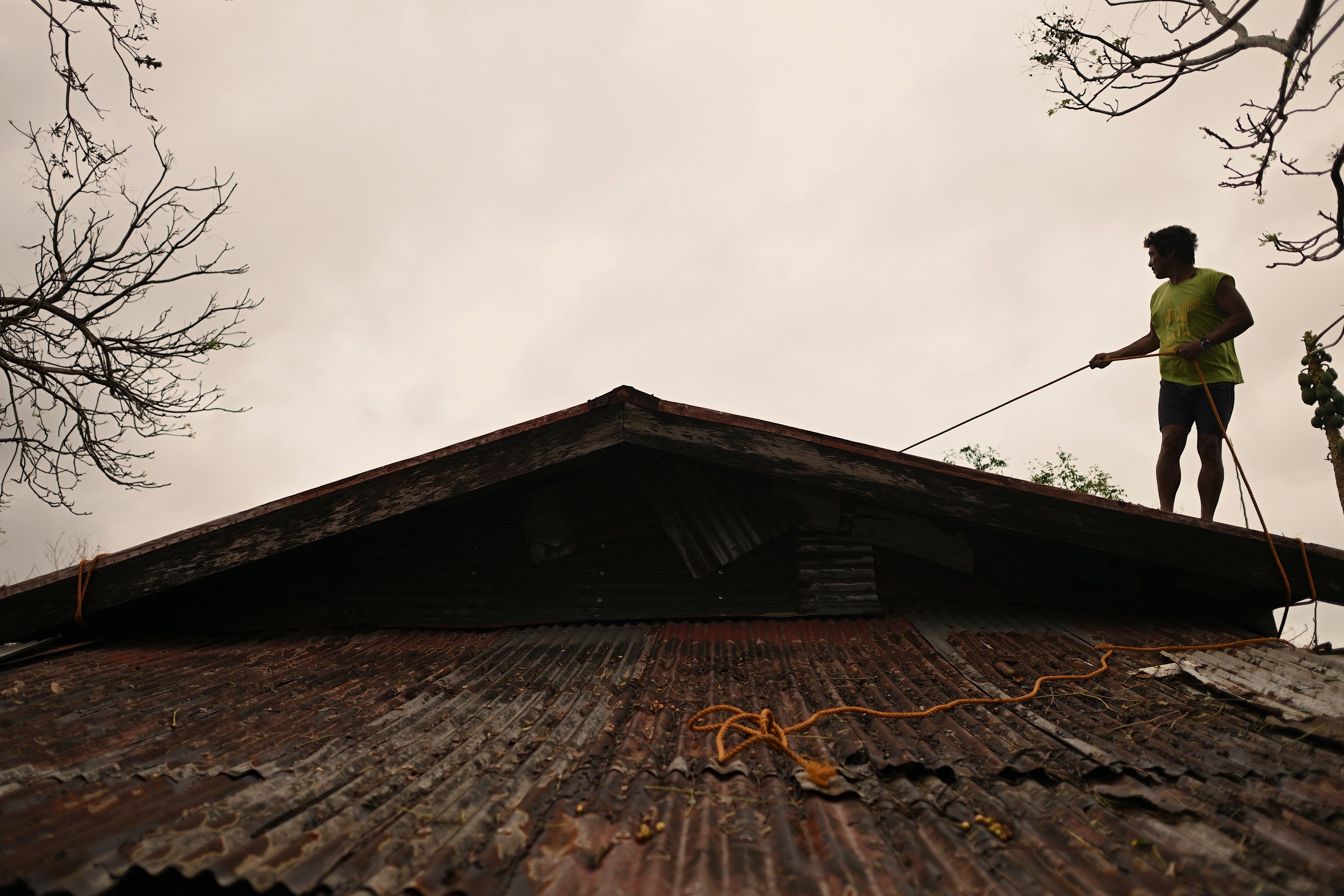 A resident reinforces the roof of his house in Santa Ana in Cagayan province of northern Philippines as they Usagi approaches on 14 November 2024