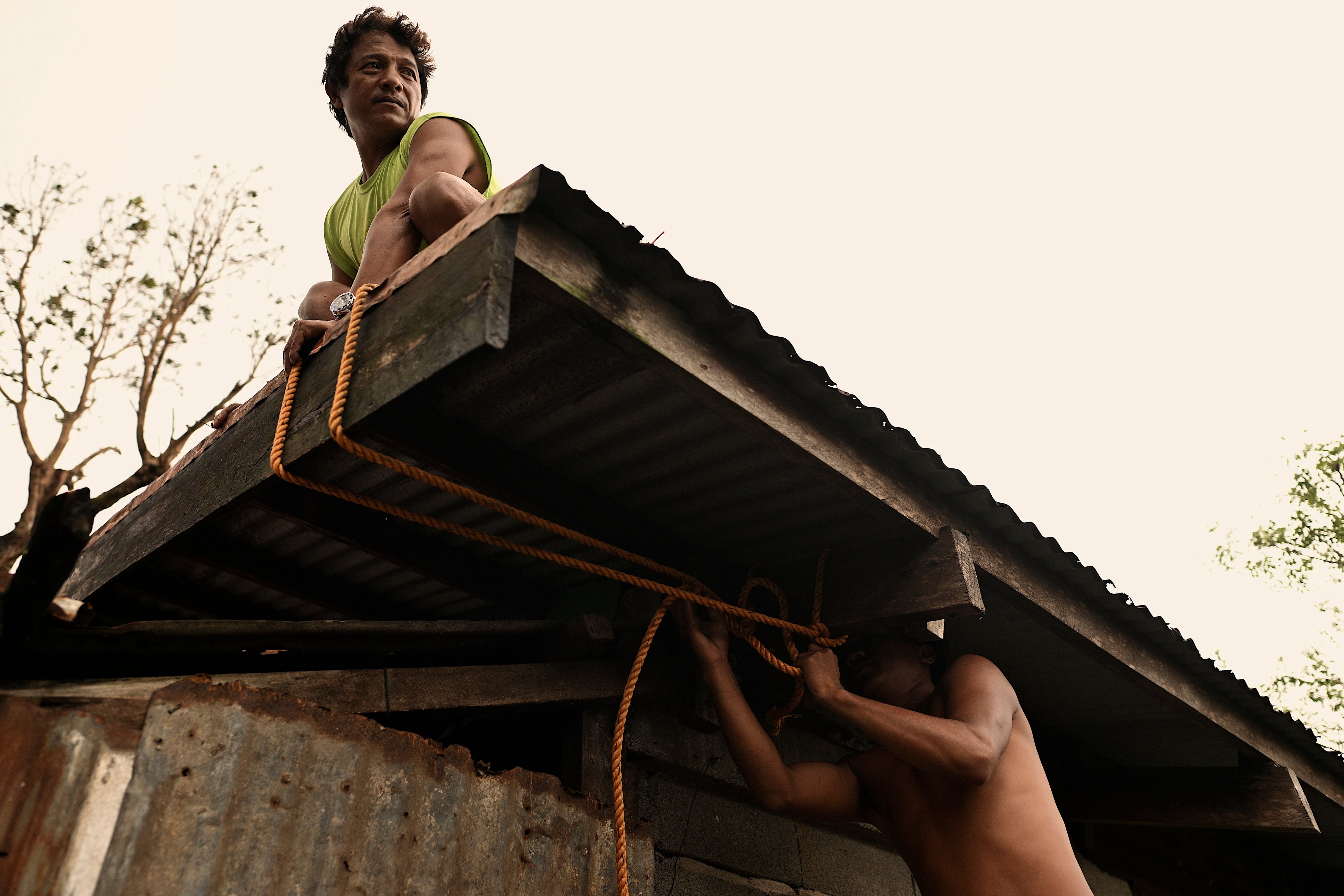 A family reinforce the roof of their house in Santa Ana in northern Philippines as Usagi approaches on 14 November 2024