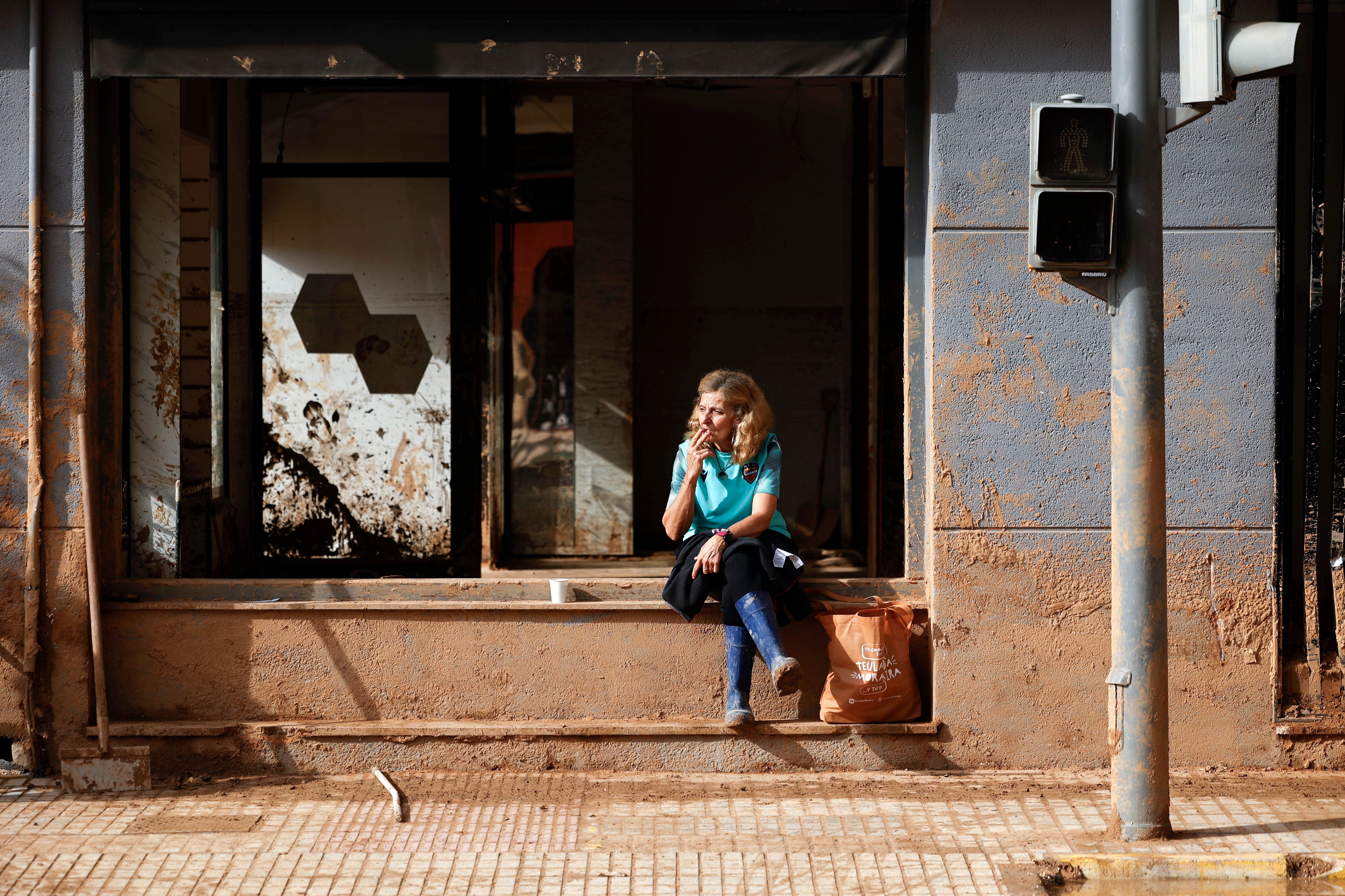 A woman takes a break during the street cleaning operation in the flood-hit municipality of Paiporta