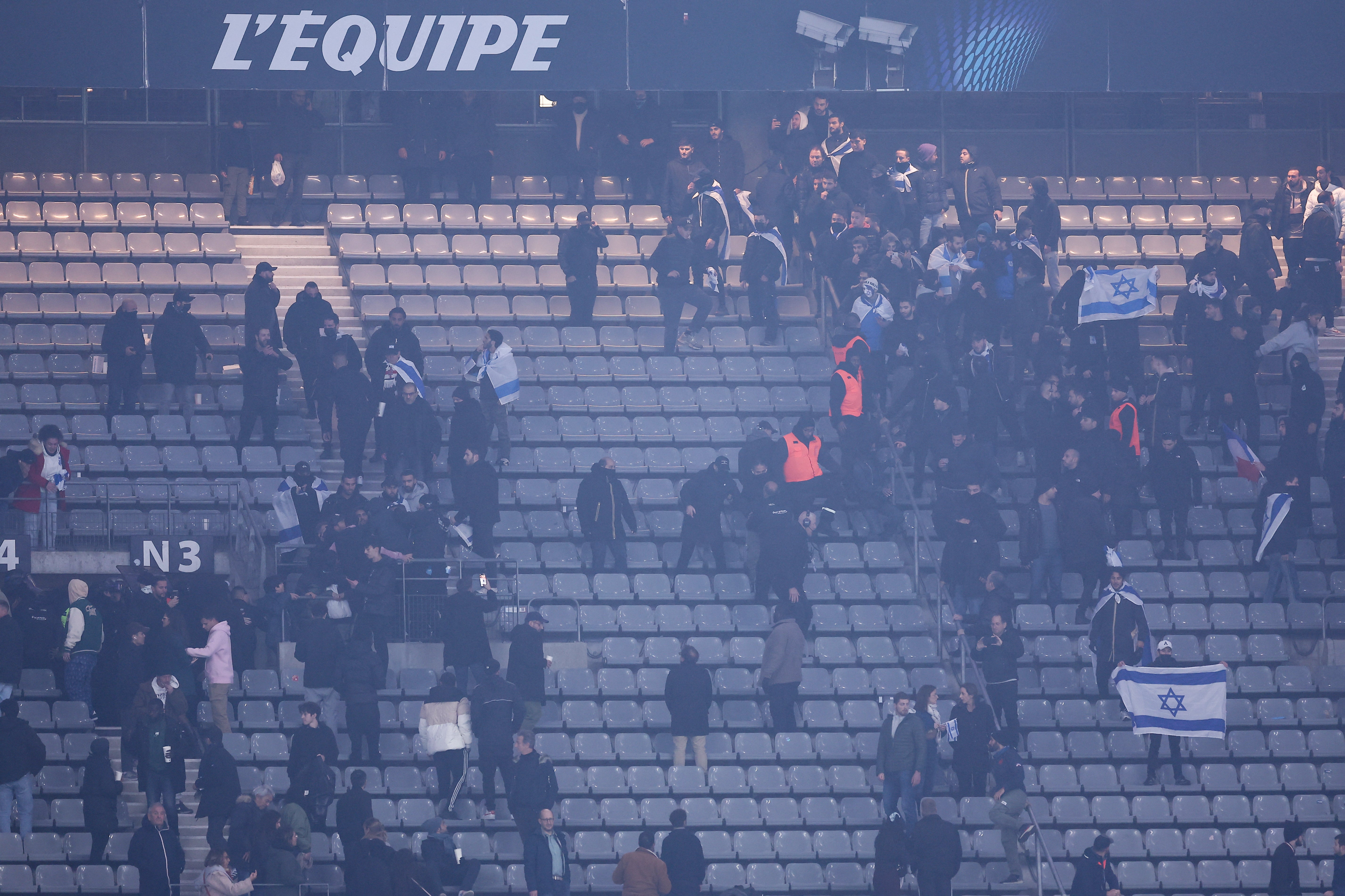 Stadium security intervene next to supporters holding Israeli flags during the UEFA Nations League match between Israel and France