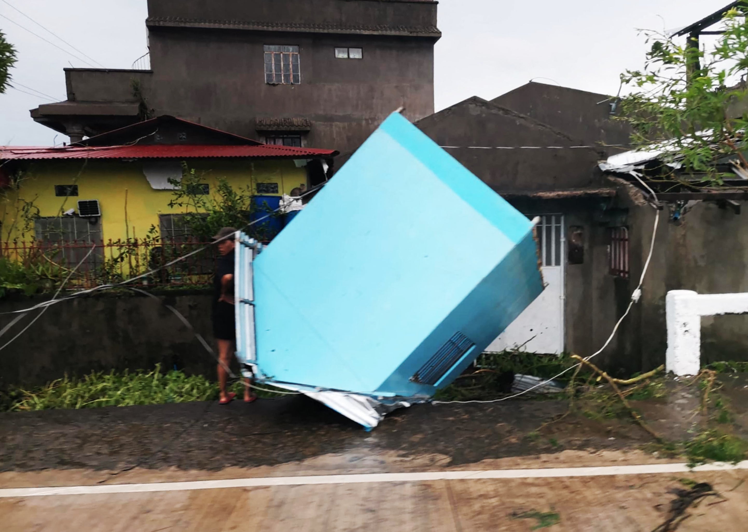 A resident standing next to a blown off kiosk along a street in Panganiban town, Catanduanes province