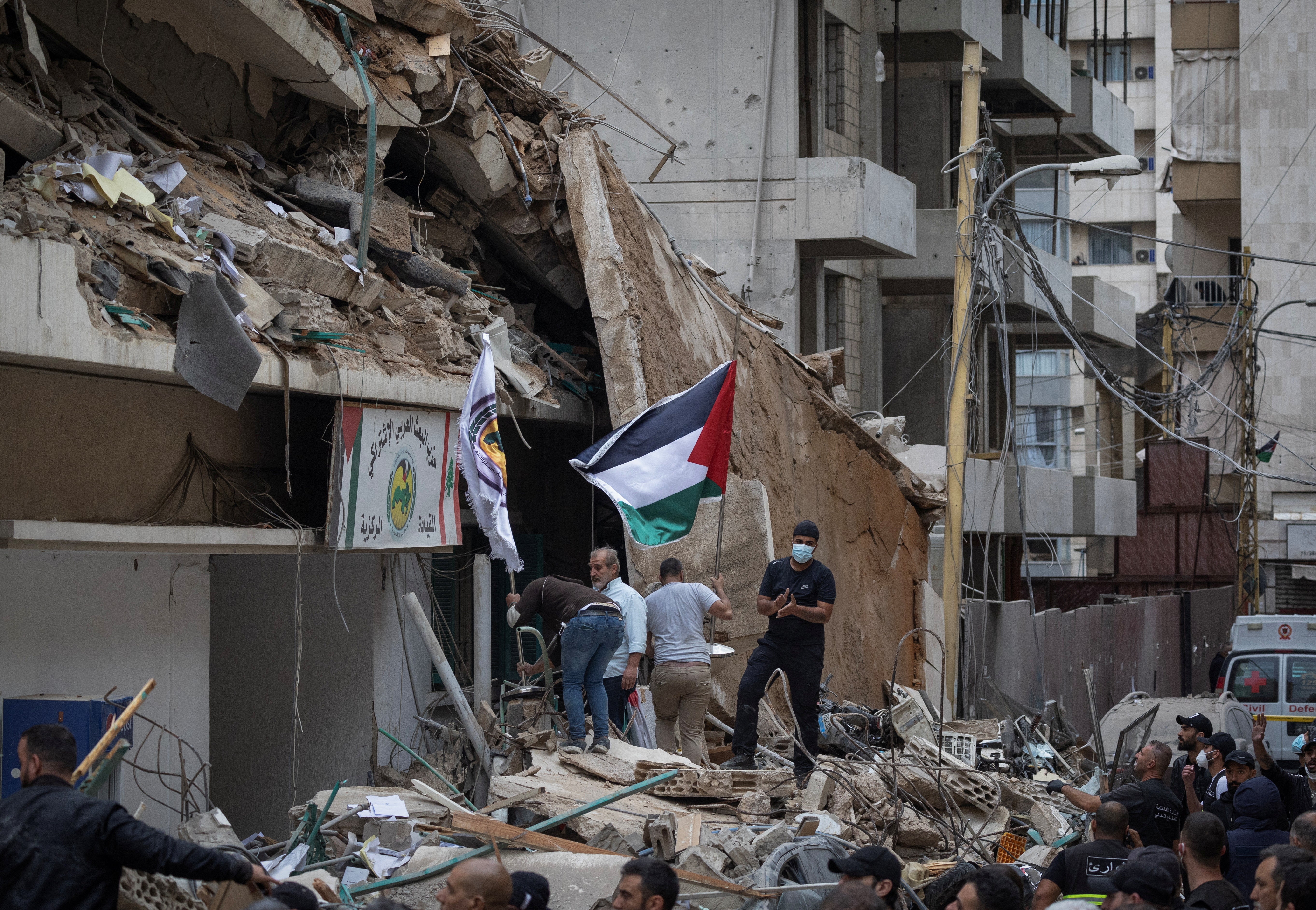 Beirut residents stand on the rubble after an Israeli strike on a building that killed Hezbollah’s media relations chief Mohammad Afif, according to security sources