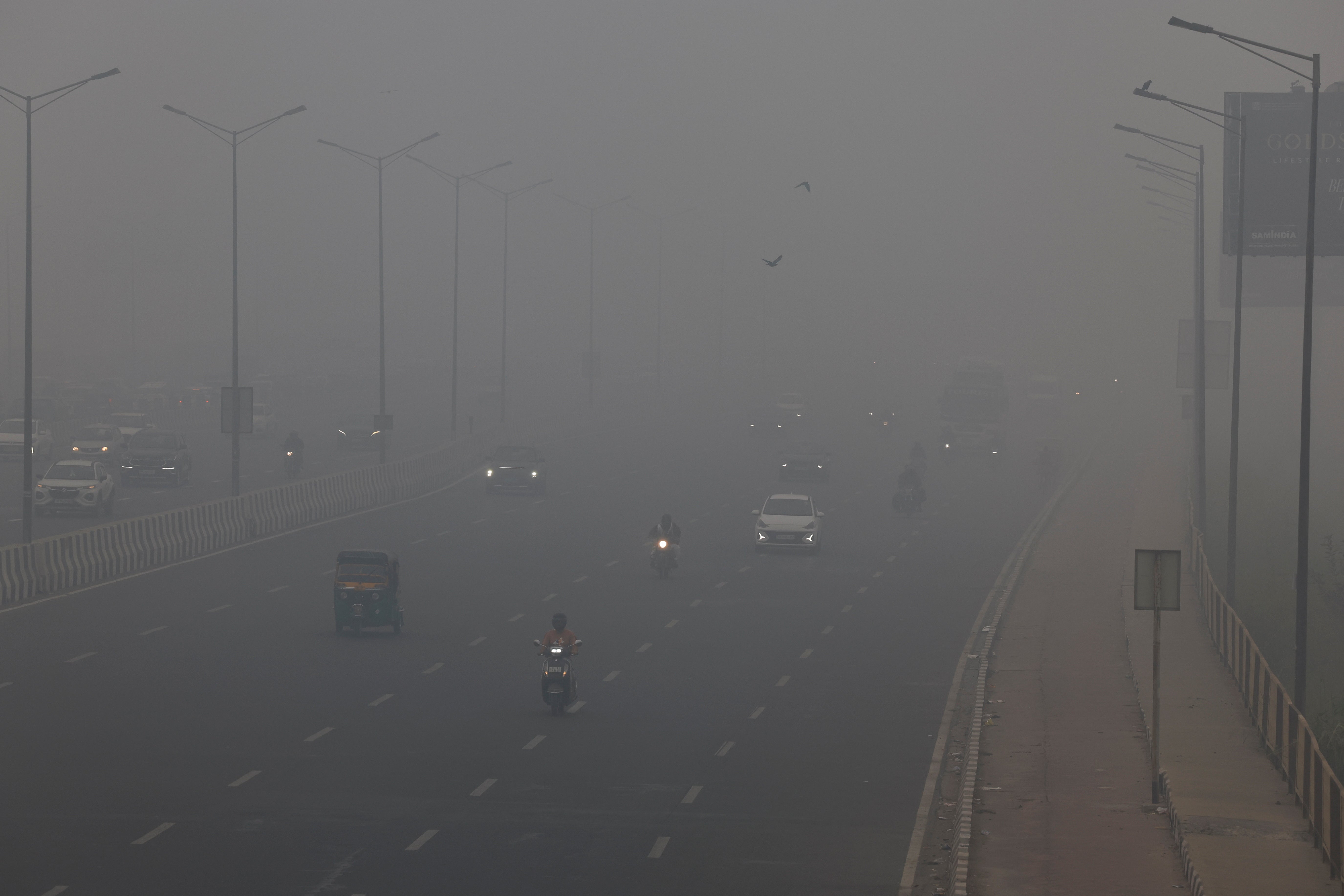 Traffic passes on a road as Delhi is enveloped by a thick layer of smog on 18 November 2024