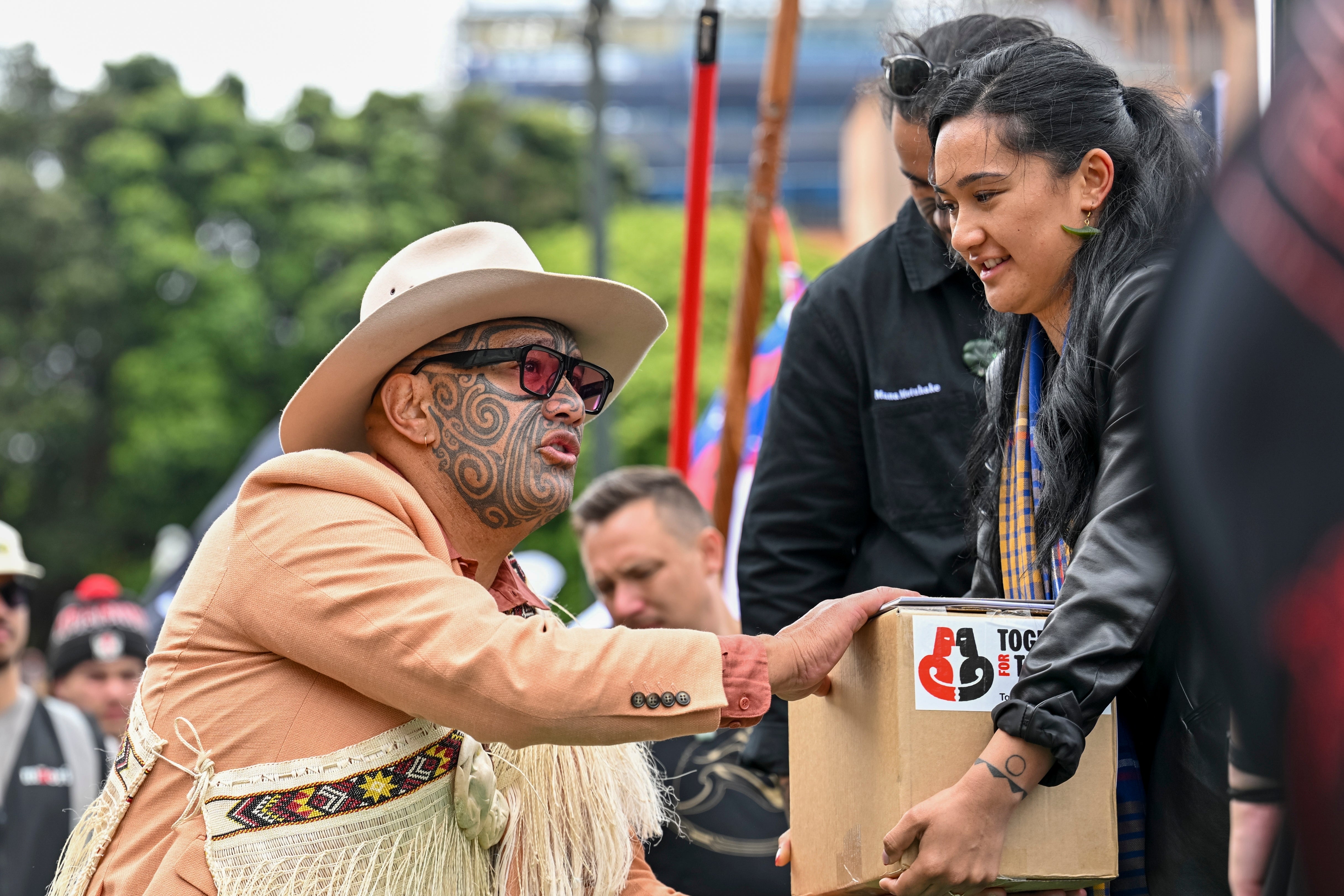 A petition is delivered to MP Rawiri Waititi, left, outside New Zealand’s parliament during a protest against a proposed law that would redefine the country's founding agreement between Indigenous Maori and the British Crown in Wellington on 19 November 2024