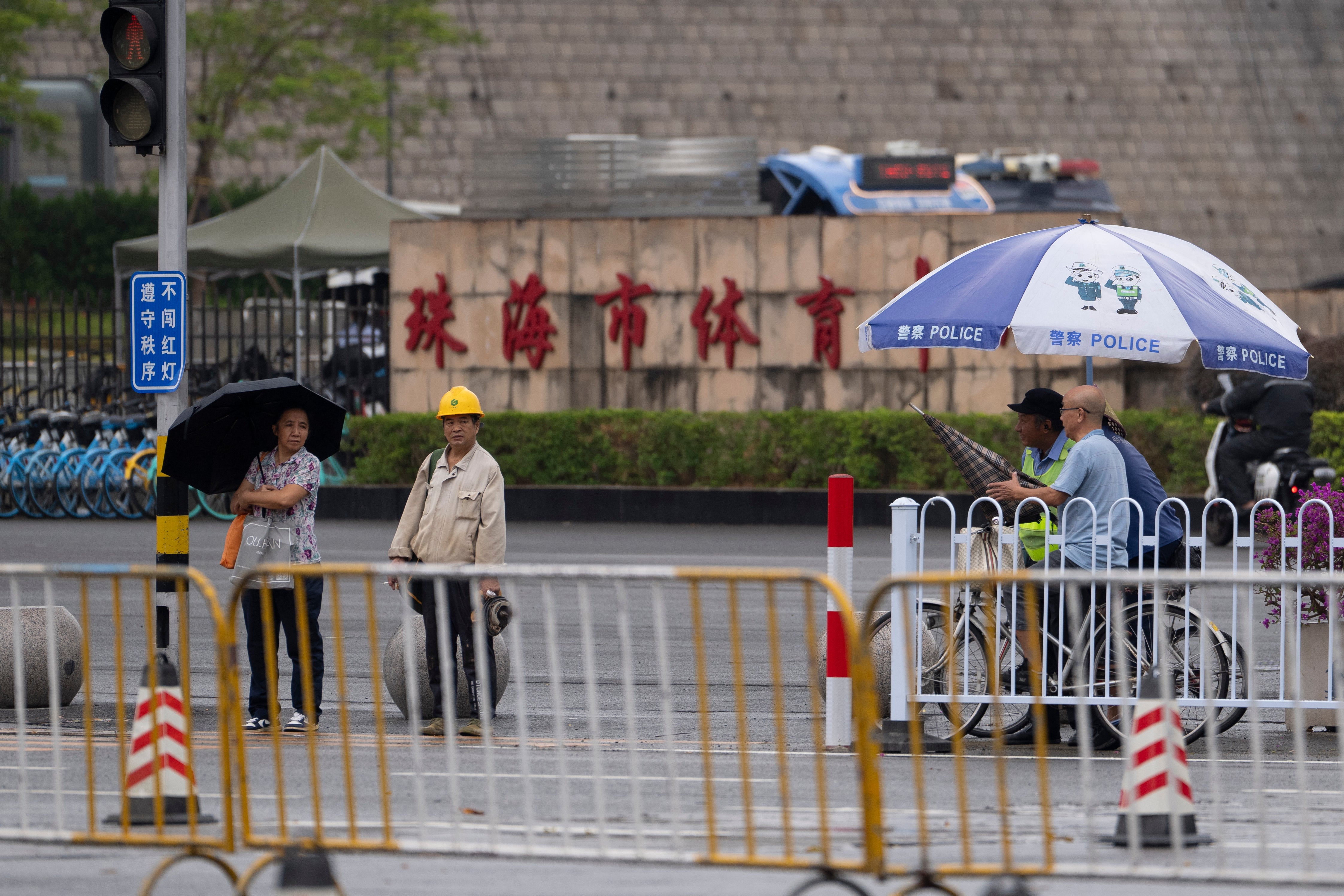 Residents pass near the sign for Zhuhai Sports Center where a man rammed his car into people exercising at the sports center, killing and injuring dozens of people in Zhuhai in southern China's Guangdong province, Nov. 14, 2024. (AP Photo/Ng Han Guan), File)