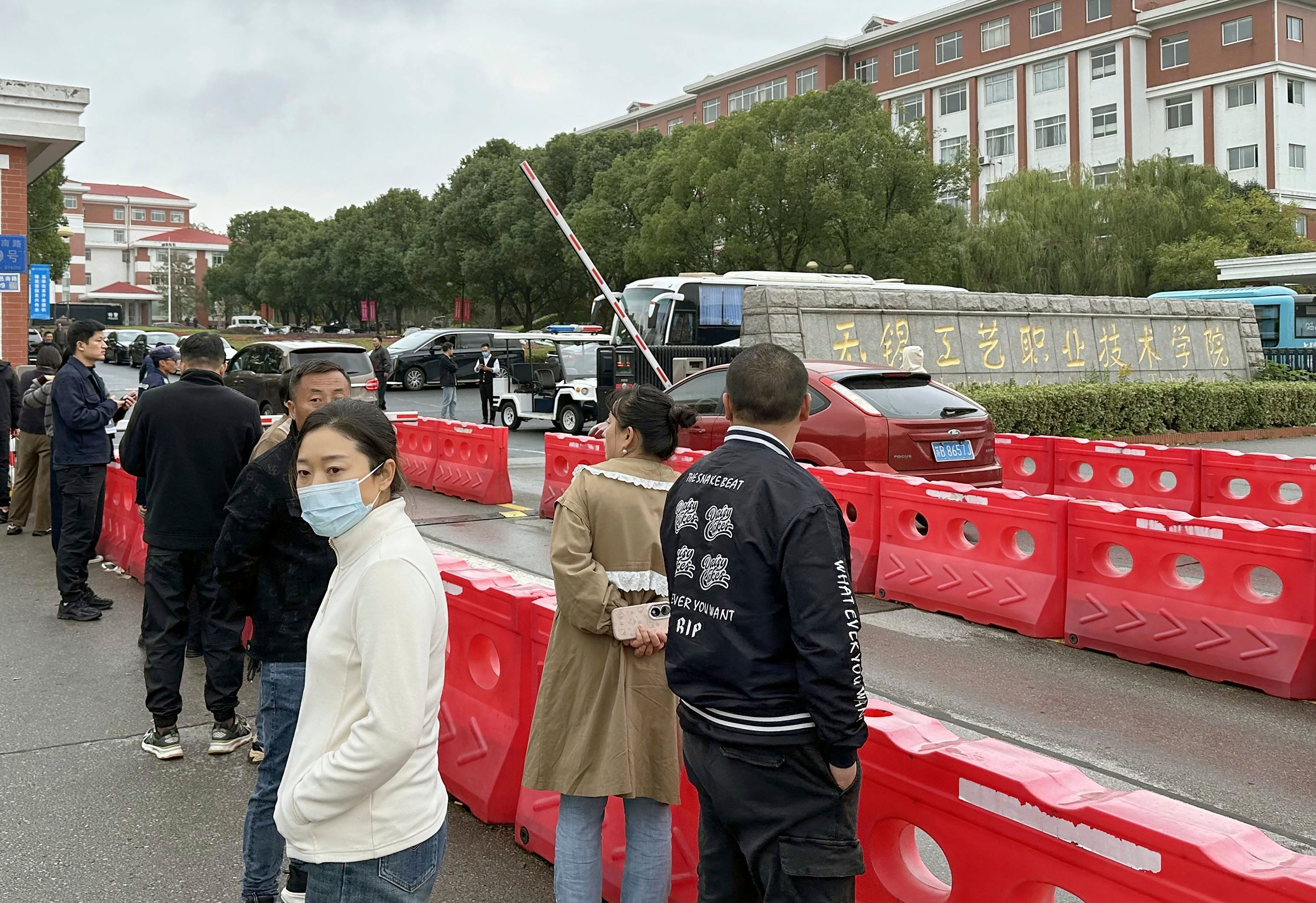 Guardians gather in front of the Wuxi Vocational Institute of Arts and Technology in Yixing, eastern Chinese city of Wuxi Sunday, Nov. 17, 2024, a day after a stabbing attack took place.