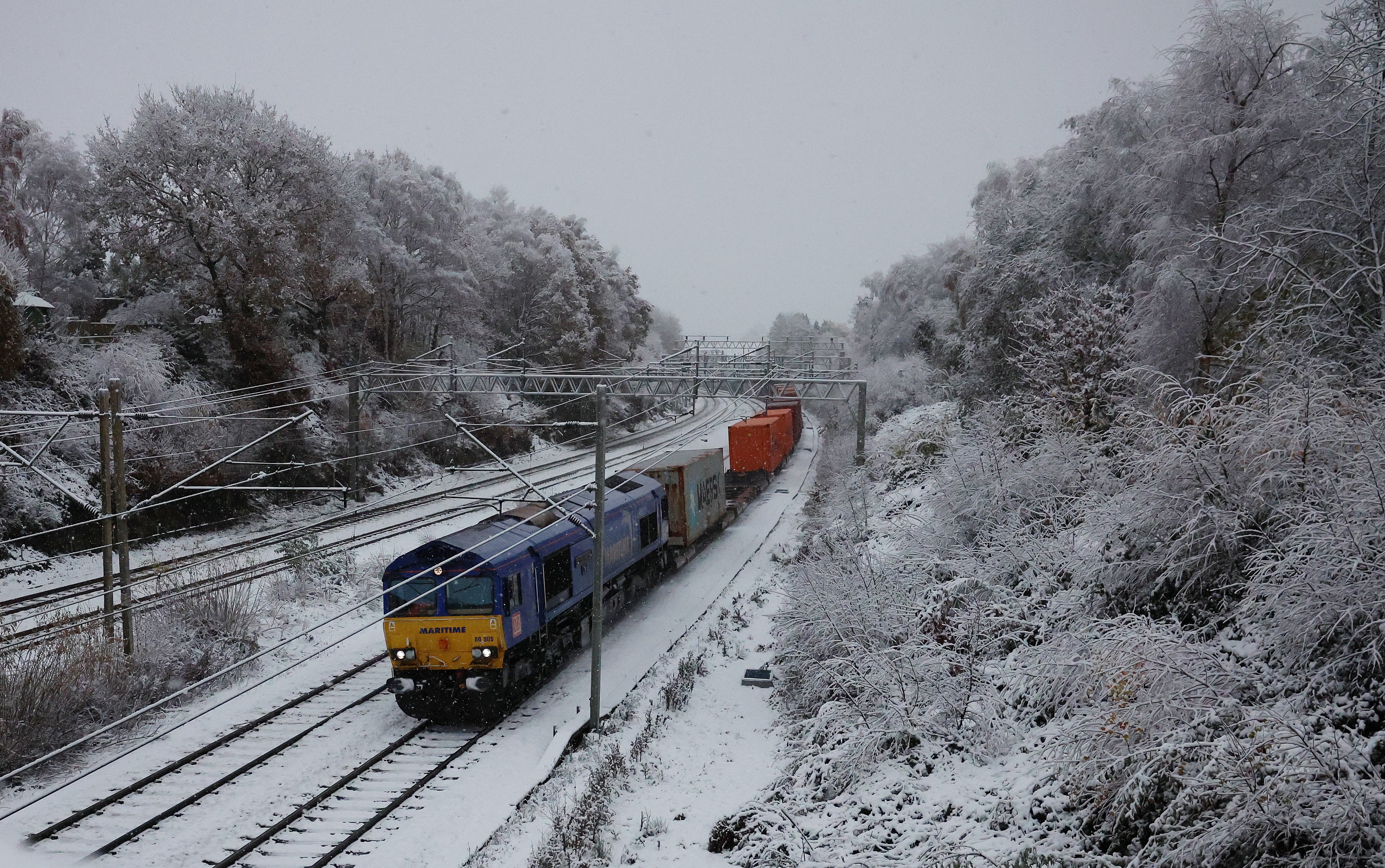 A freight train passes through snow-covered tracks in Newcastle-Under-Lyme