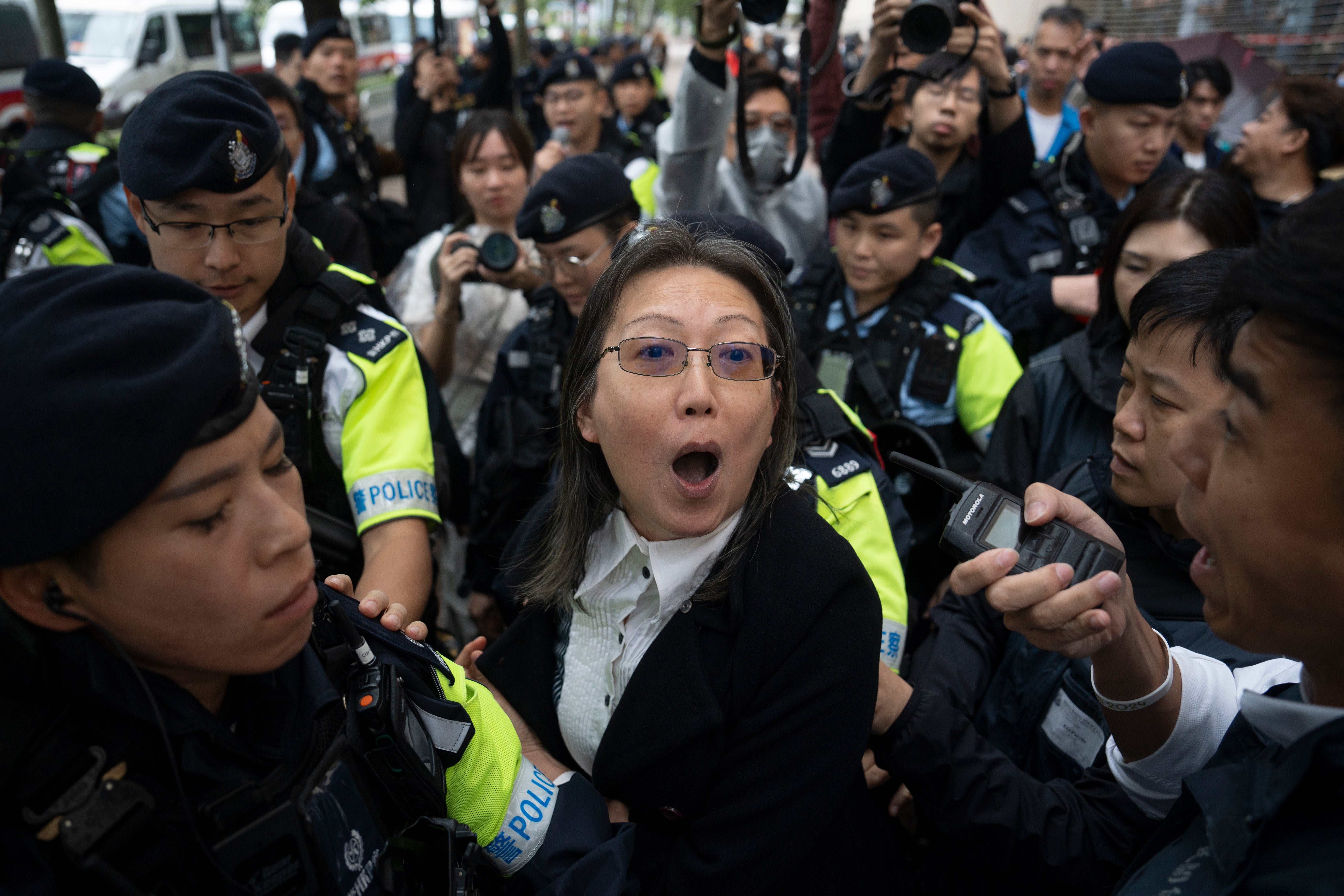 A woman is stopped by police outside the West Kowloon Magistrates Court in Hong Kong on 19 November 2024