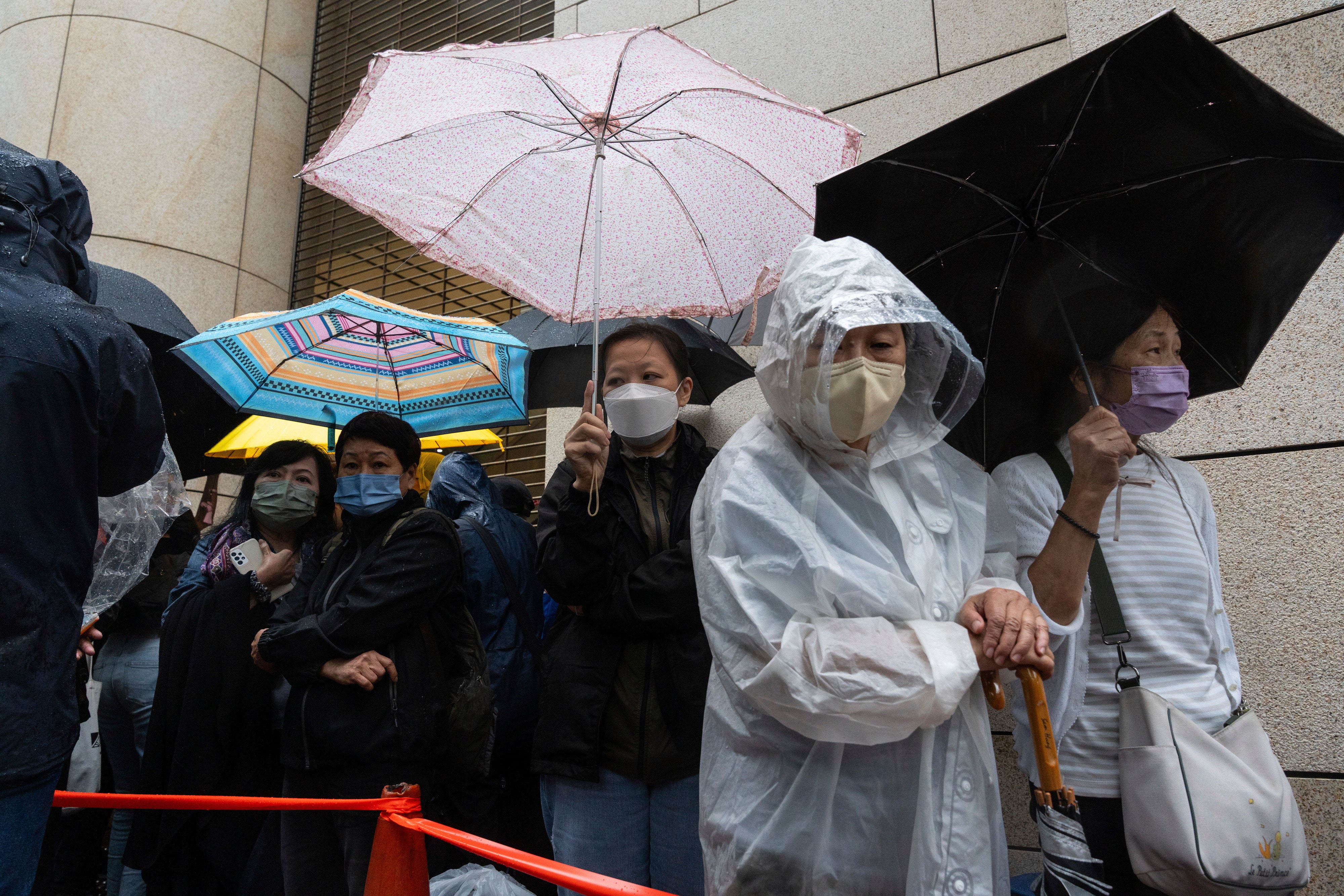 People wait outside the West Kowloon Magistrates Courts in Hong Kong on 19 November2024