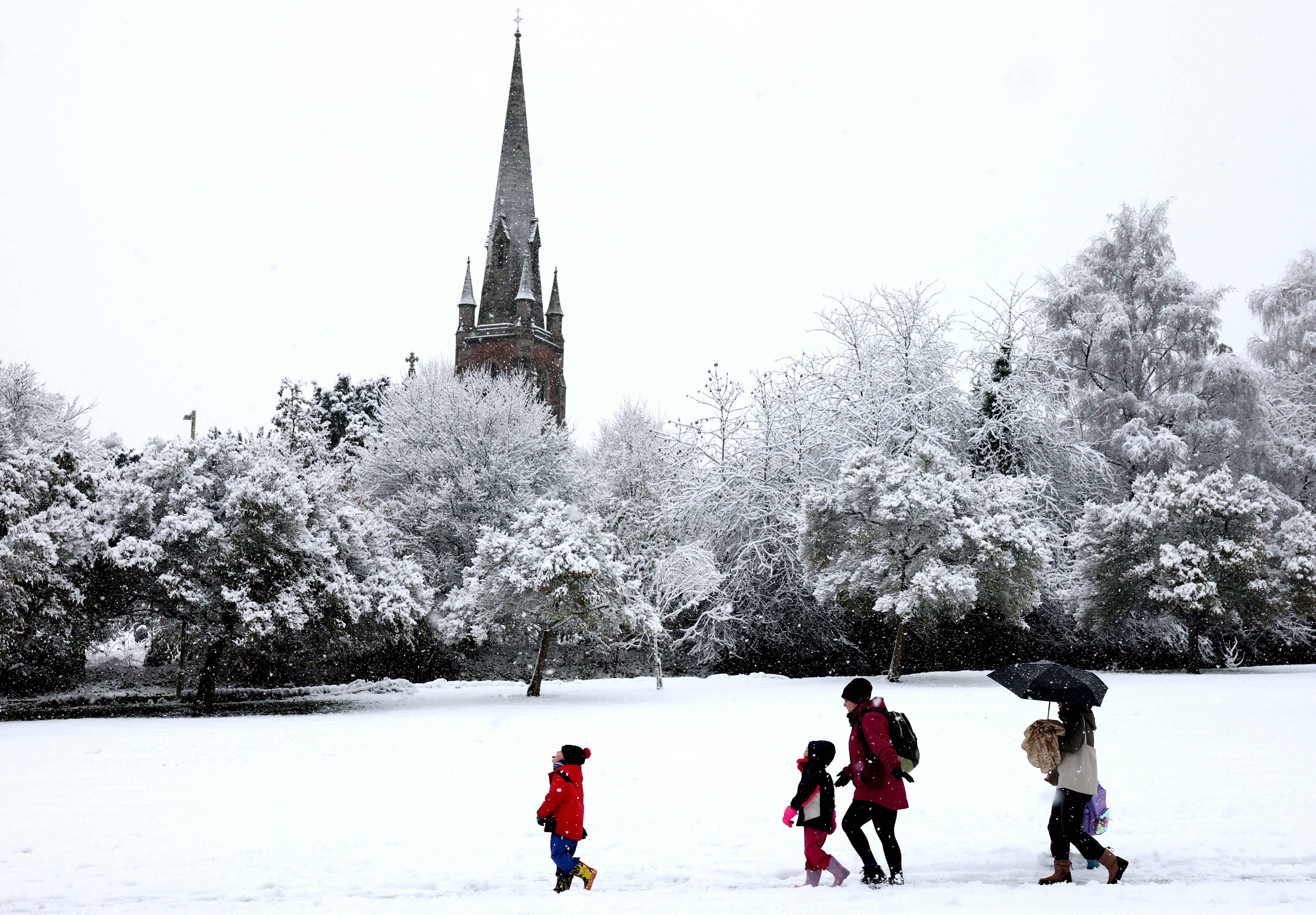 A family walk past the snow-dusted St John’s Parish Church in Keele on 19 November