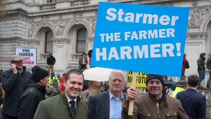 Robert Jenrick poses under a ‘Starmer the farmer harmer’ banner