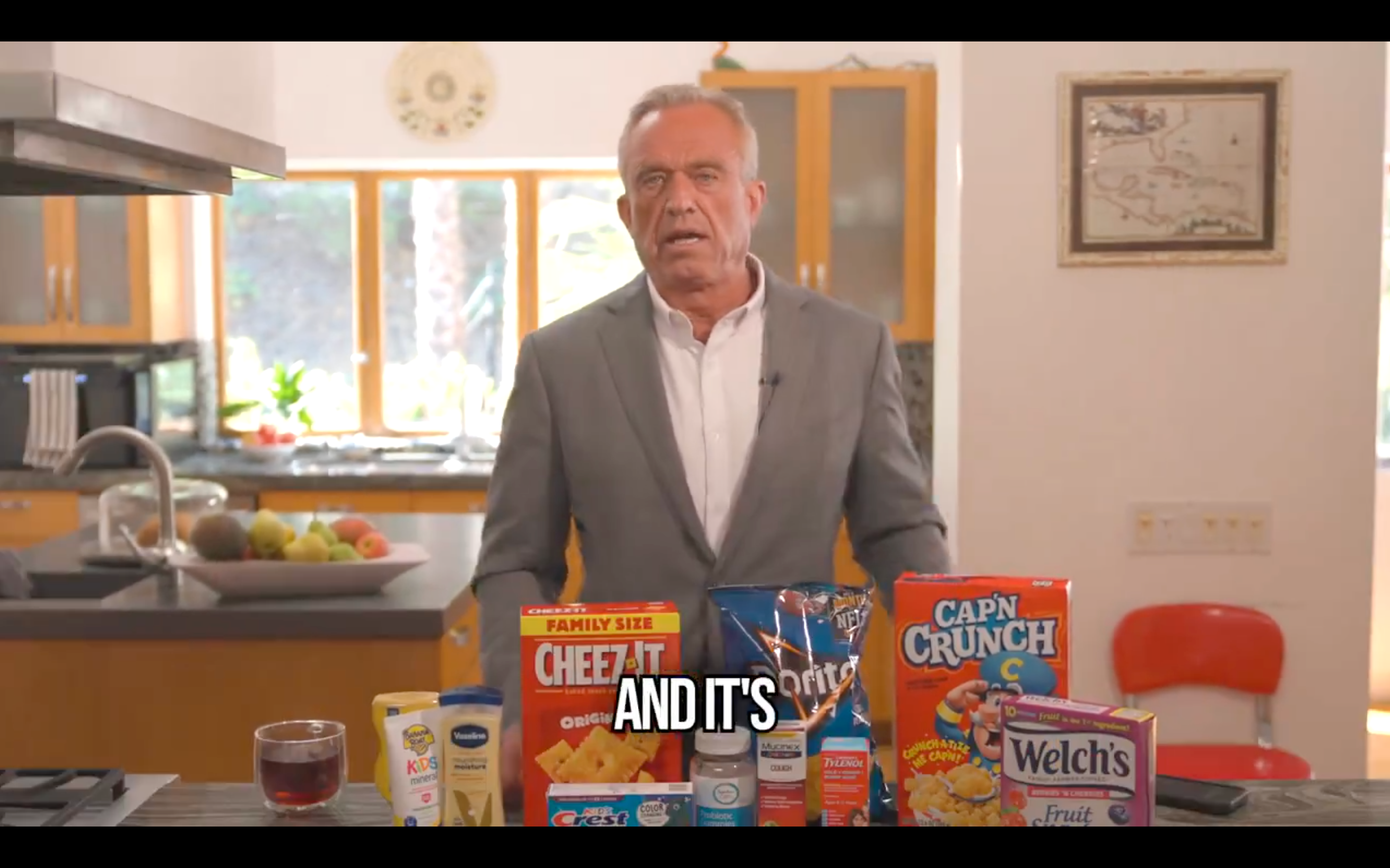 RFK Jr discussing the problems with processed foods while standing in front of a Doritos bag and a Cap’n Crunch cereal box