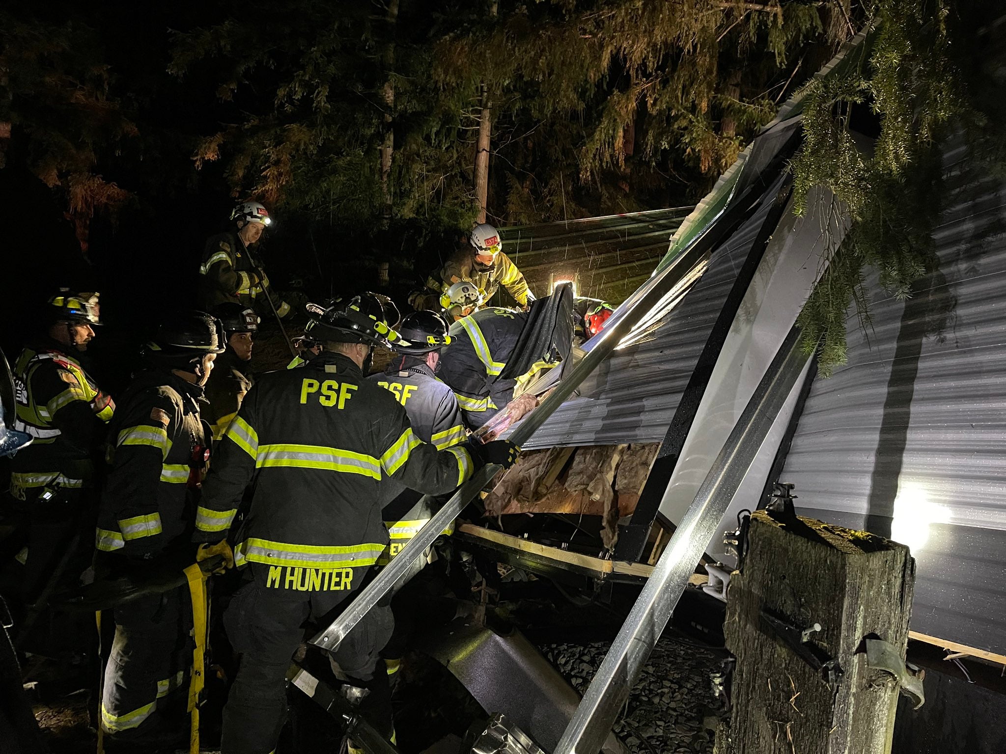 Puget Sound firefighters work to rescue two people who were injured after a tree fell on their trailer. The individuals, who were not identified, were taken to the hospital