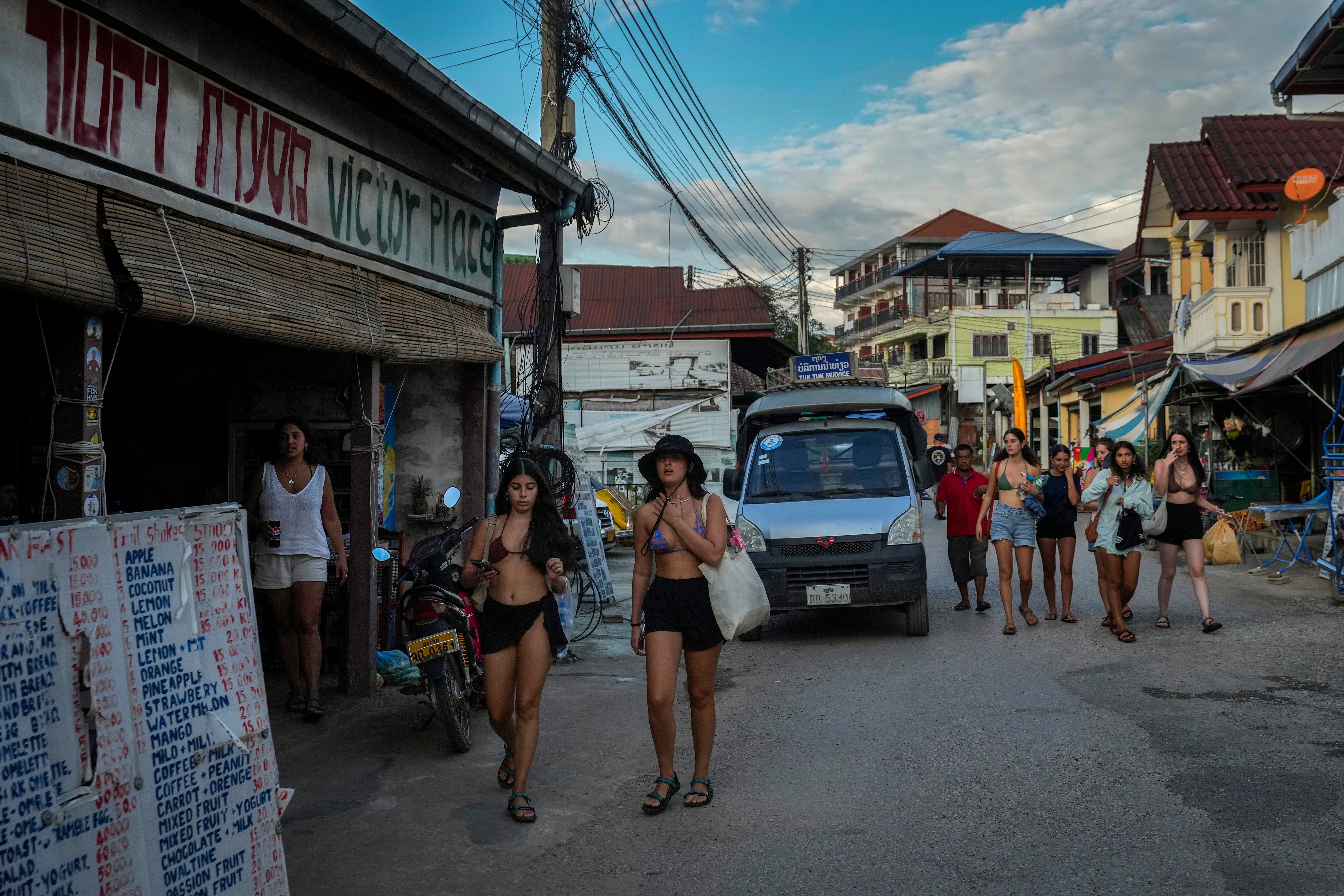 Foreign tourists walk in a street near bars in Vang Vieng, Laos