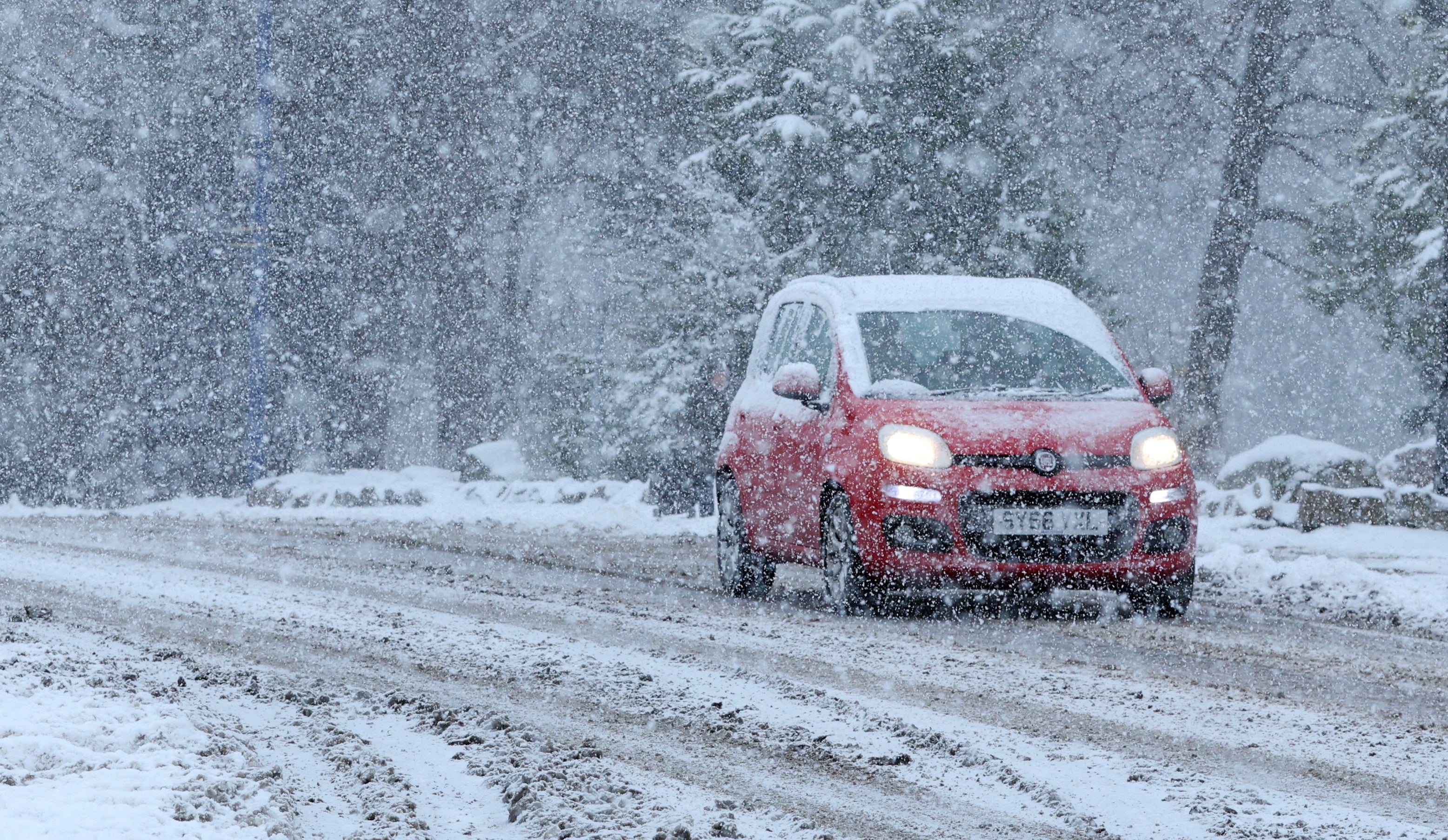 A car drives through the snow in Aviemore, Scotland