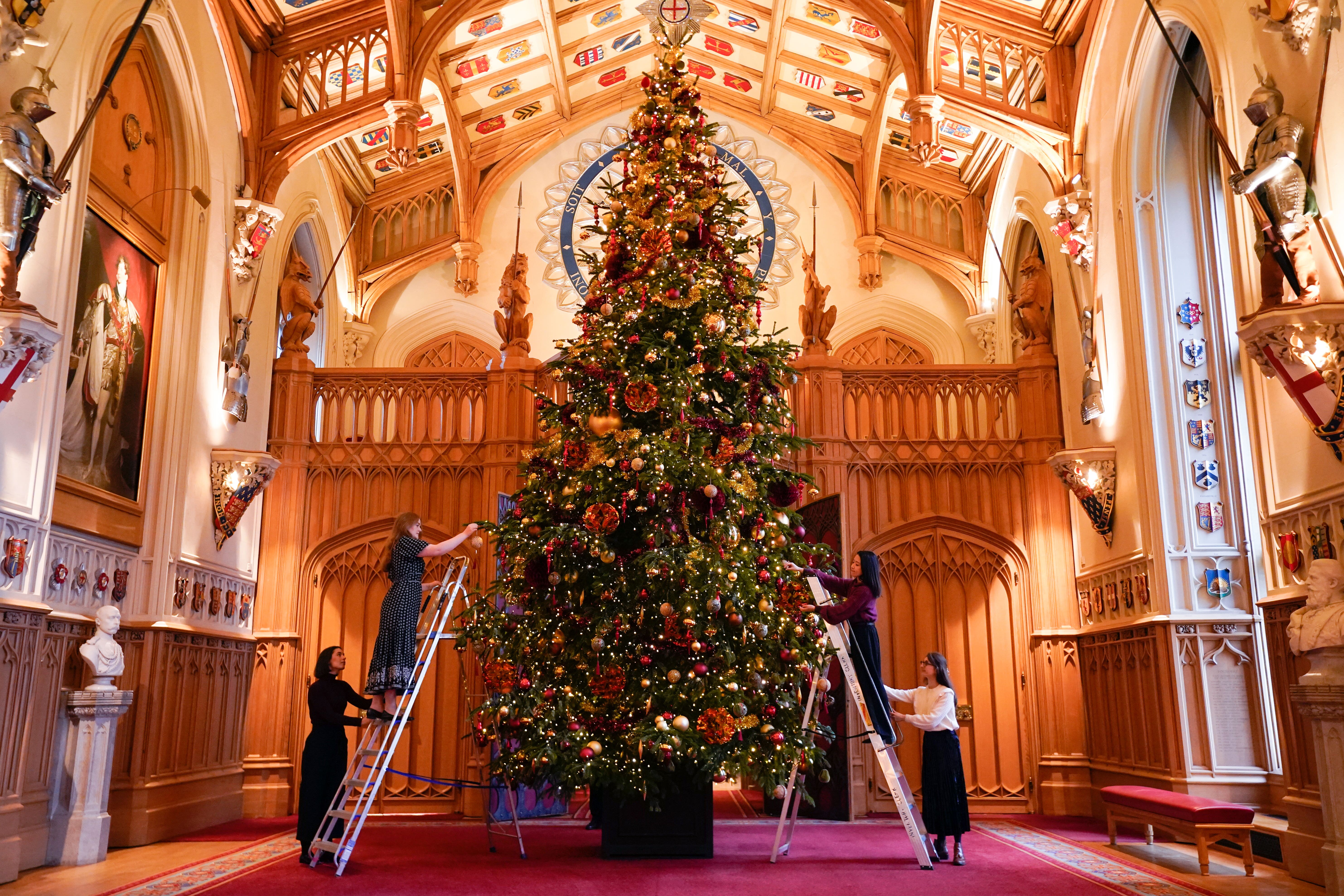 Royal Collection Trust staff add the finishing touches to a Christmas tree in St George’s Hall, Windsor Castle (Andrew Matthews/PA)