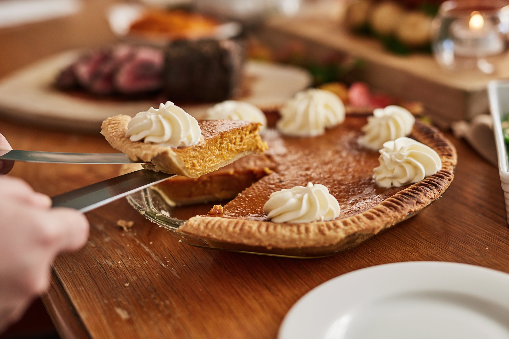 A person picks up a piece of pumpkin pie. Pumpkin production is threatened by extremes brought by climate change