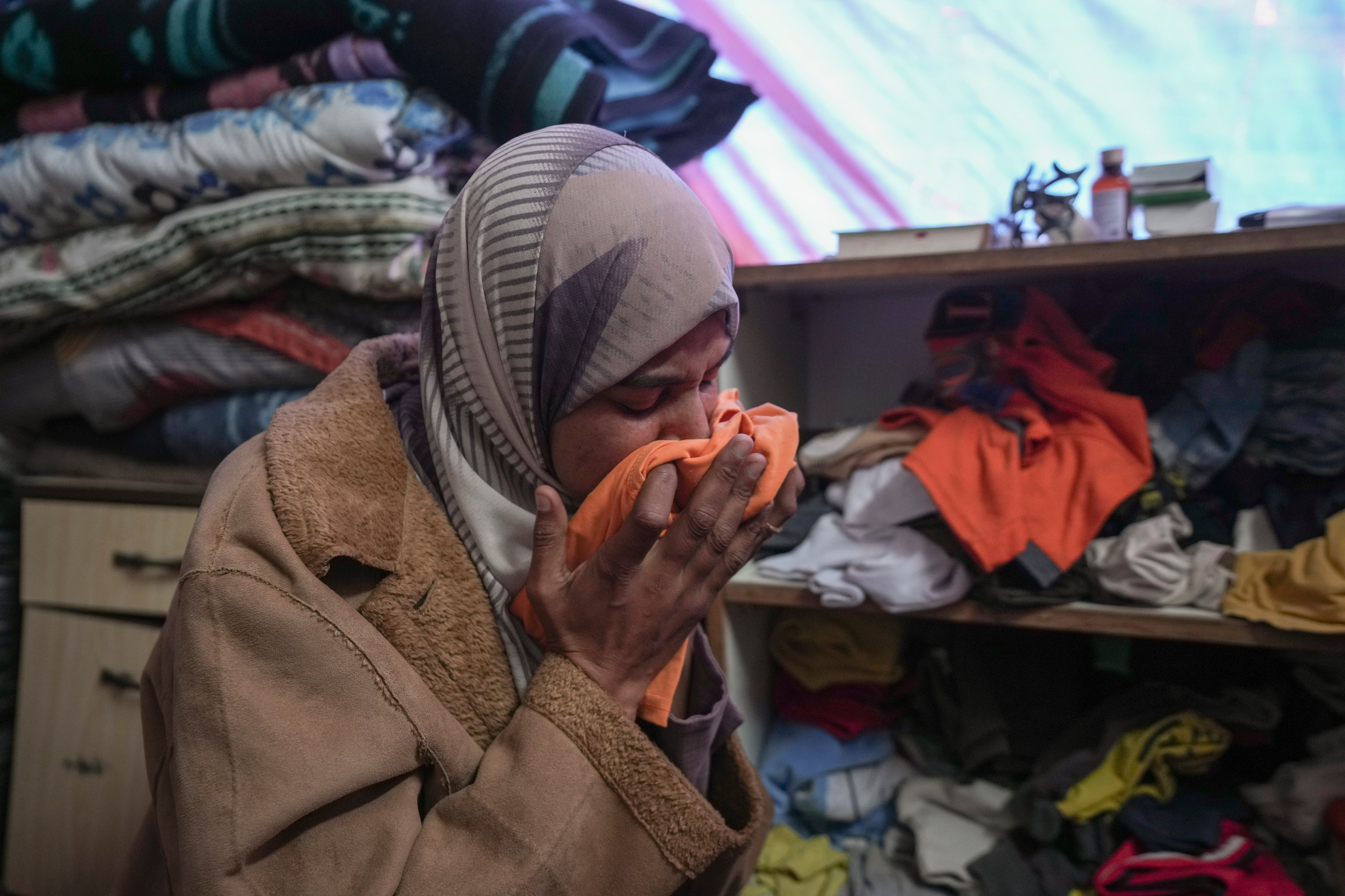 Areej al Qadi weeps of one of her children’s clothes after the funeral of her three children in Khan Younis, Gaza Strip, Thursday 21 November 2024