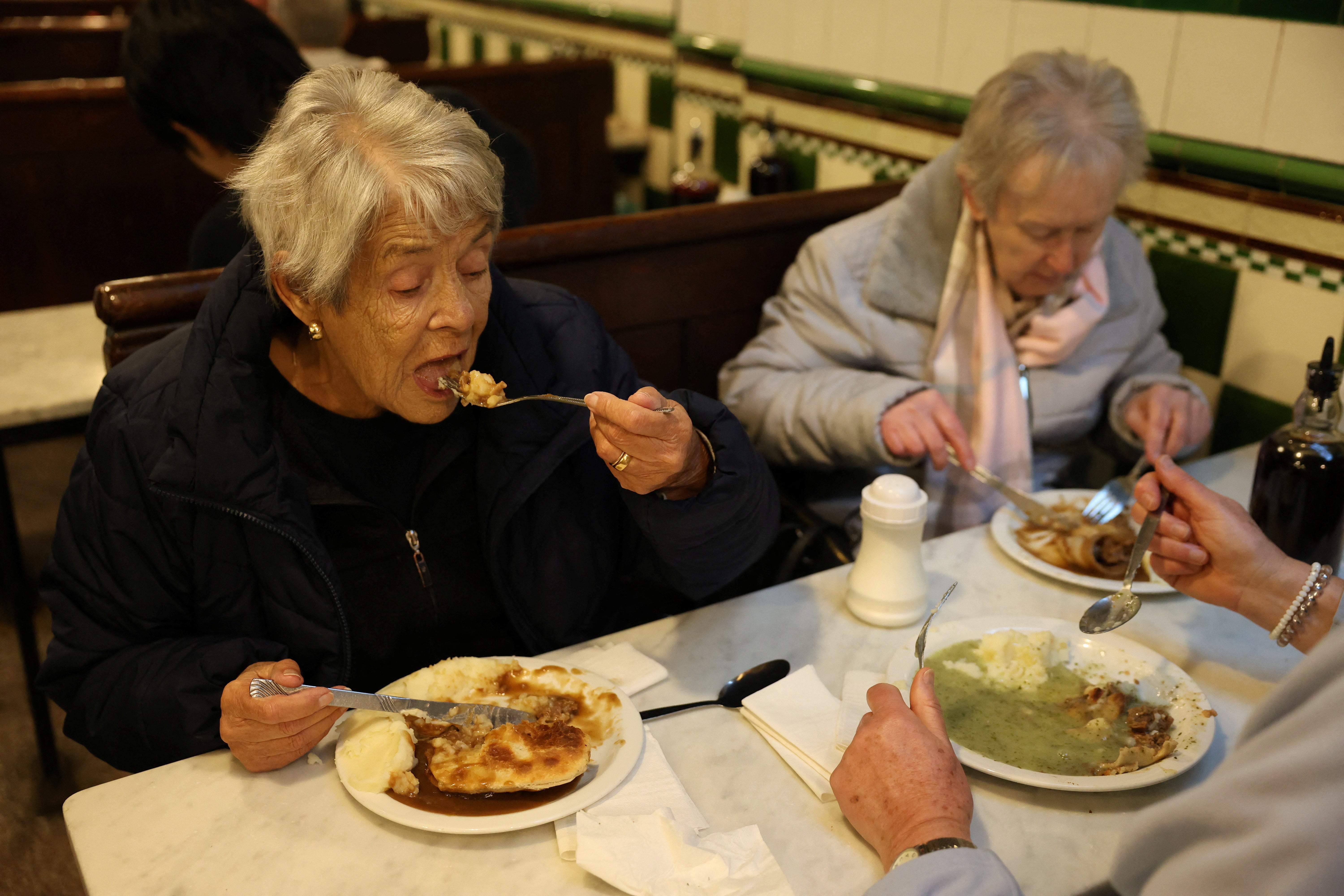 Fay Prestidge and Maureen Komjati, eat pie and mash at M. Manze, in London, Britain, November 21, 2024. REUTERS/Mina Kim