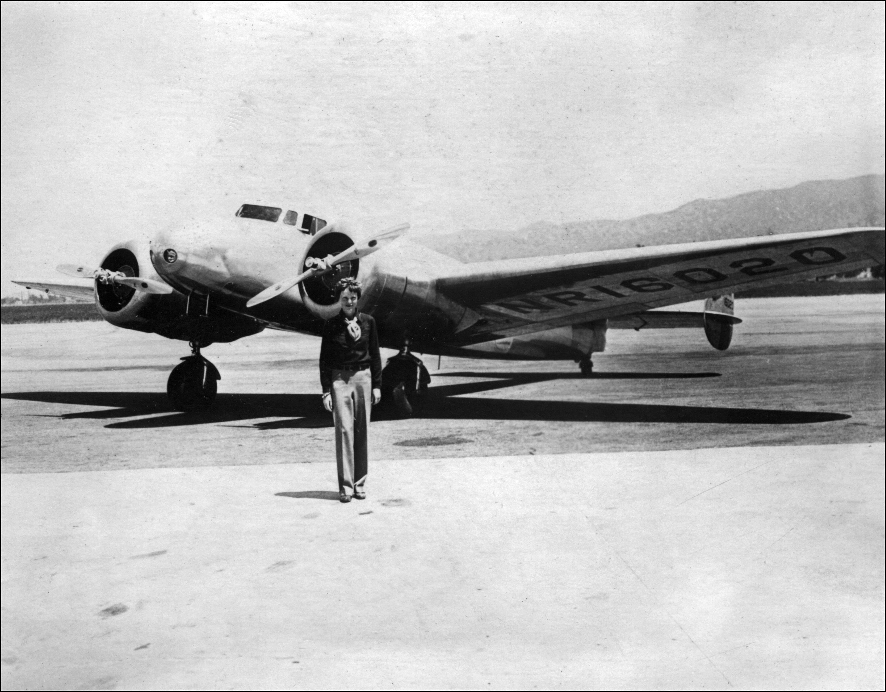 American female aviator Amelia Earhart stands in front of her plane. In 1937, with navigator Fred Noonan, she set out to fly around the world. But, their plane was lost over the Pacific in July