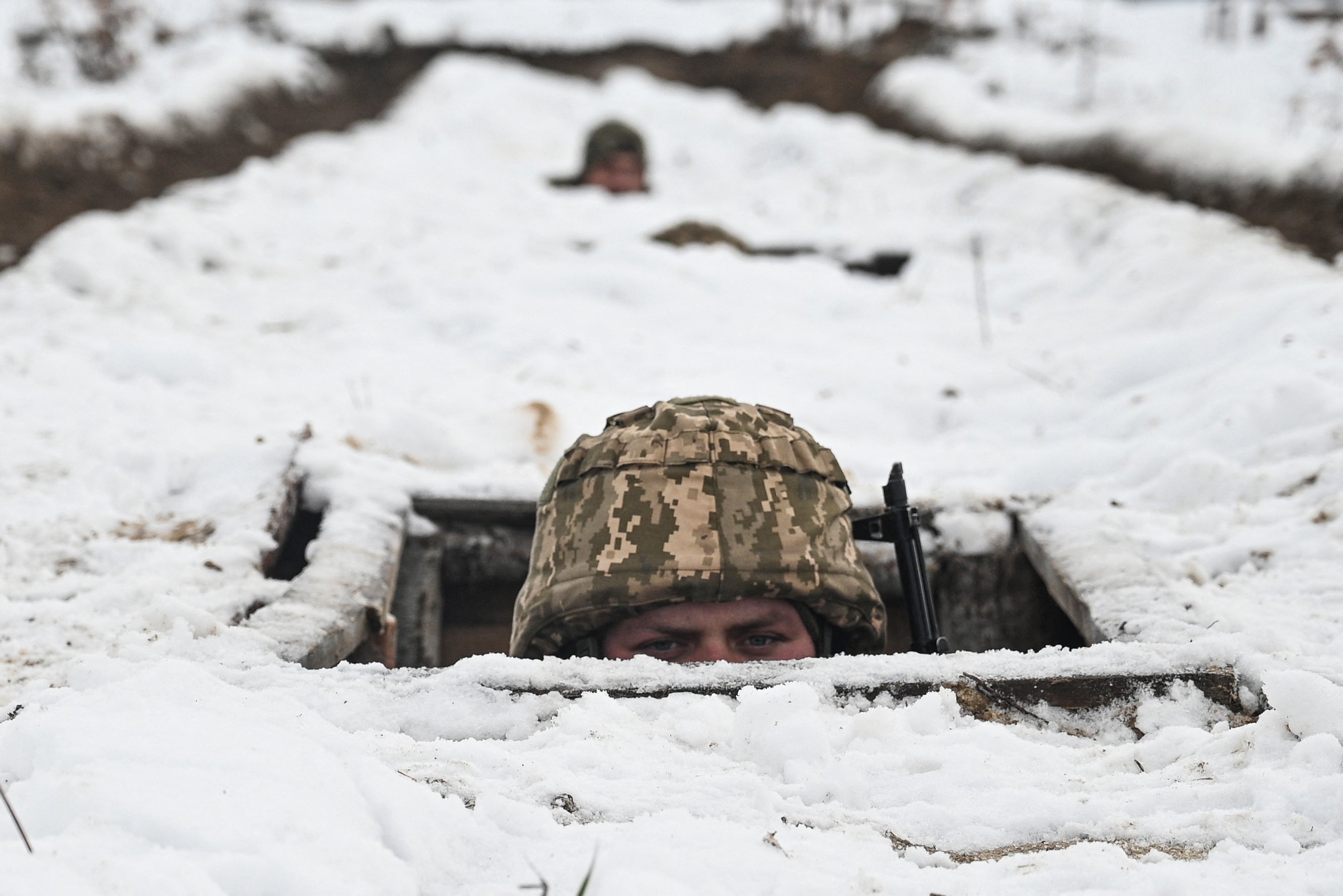 A Ukrainian soldier’s head appears above the ground during a training exercise