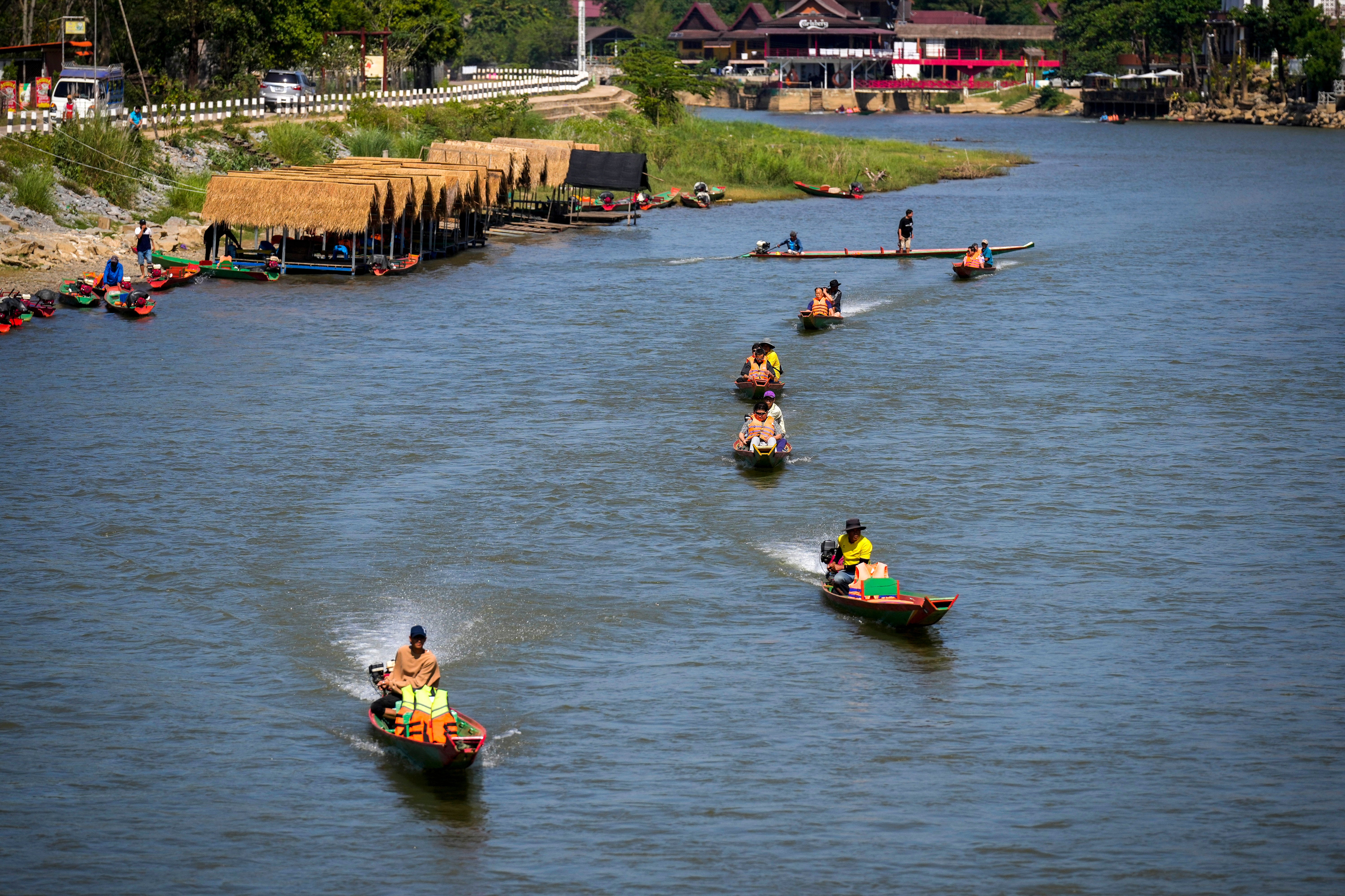 Foreign tourists ride boats along the river in Vang Vieng on Friday amid concerns over methanol poisoning at the backpacking hotspot