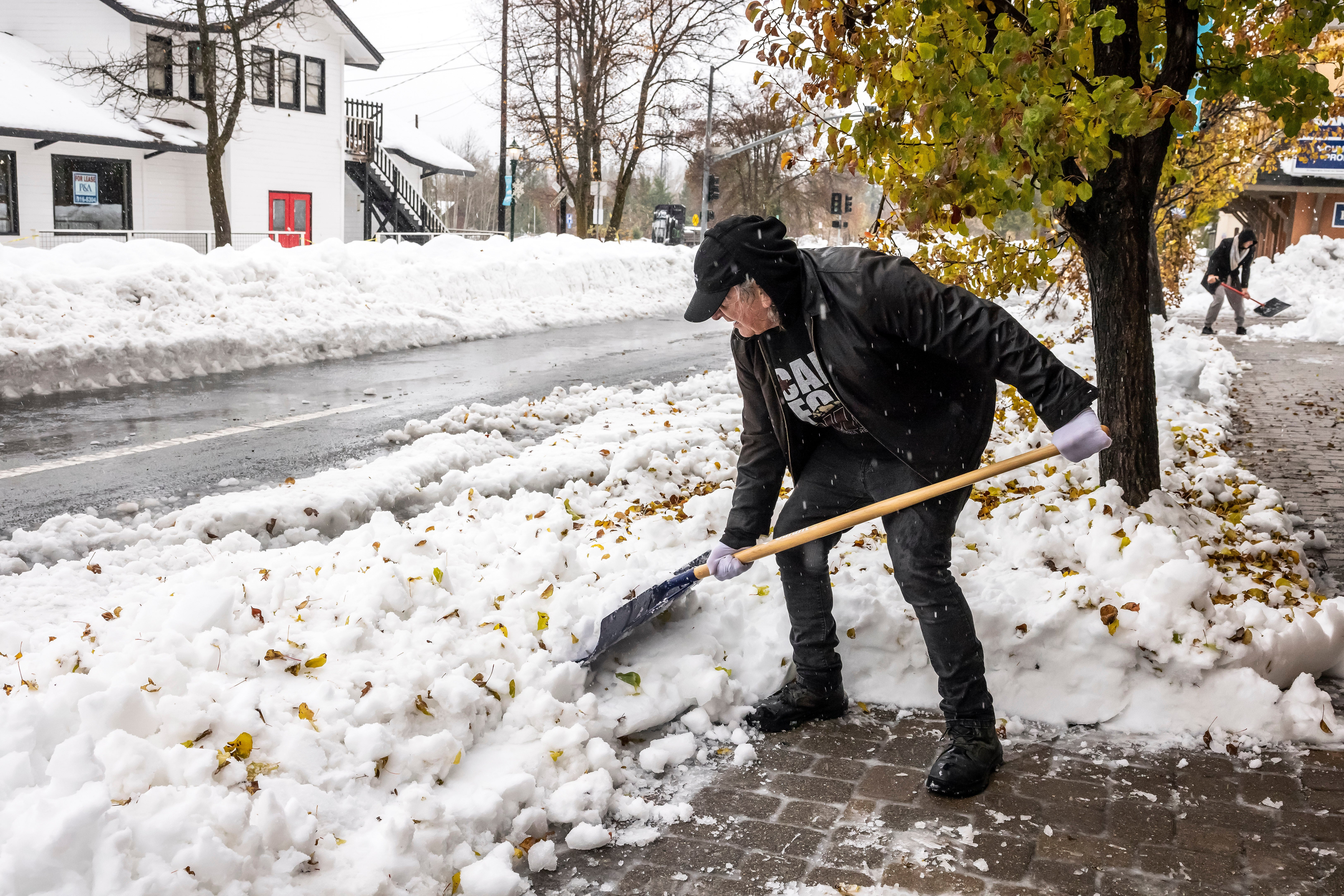 Salvador Garza shovels snow from the front of his shop Crystal Tones in Mt. Shasta, California, on Thursday. More snow was falling Friday morning