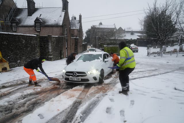 <p>People help a driver in the snow in Stirling, Scotland, during Storm Bert on Saturday</p>