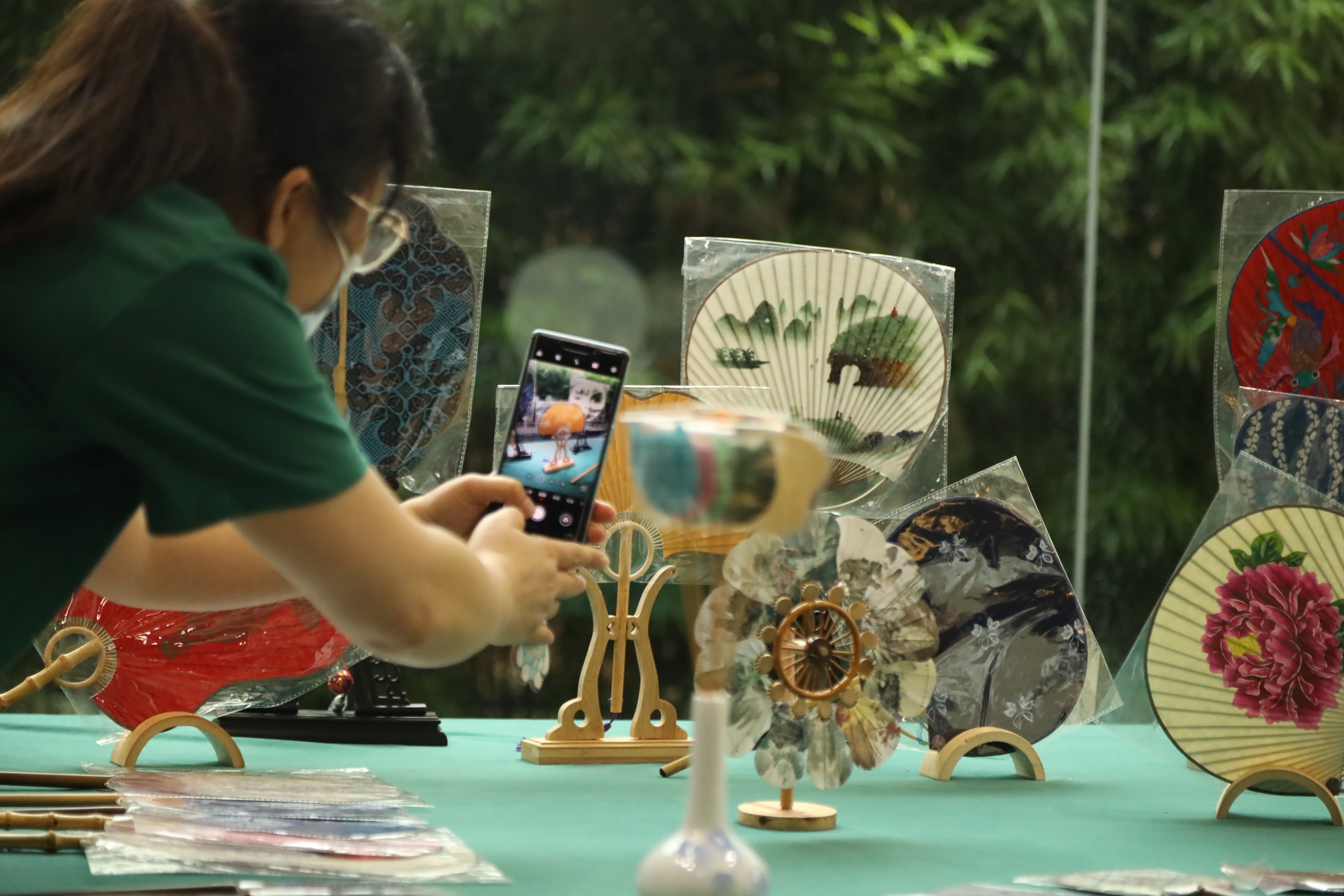 A visitor takes photos of Chinese tuanshan fans exhibited in May in Guilin, Guangxi Zhuang autonomous region