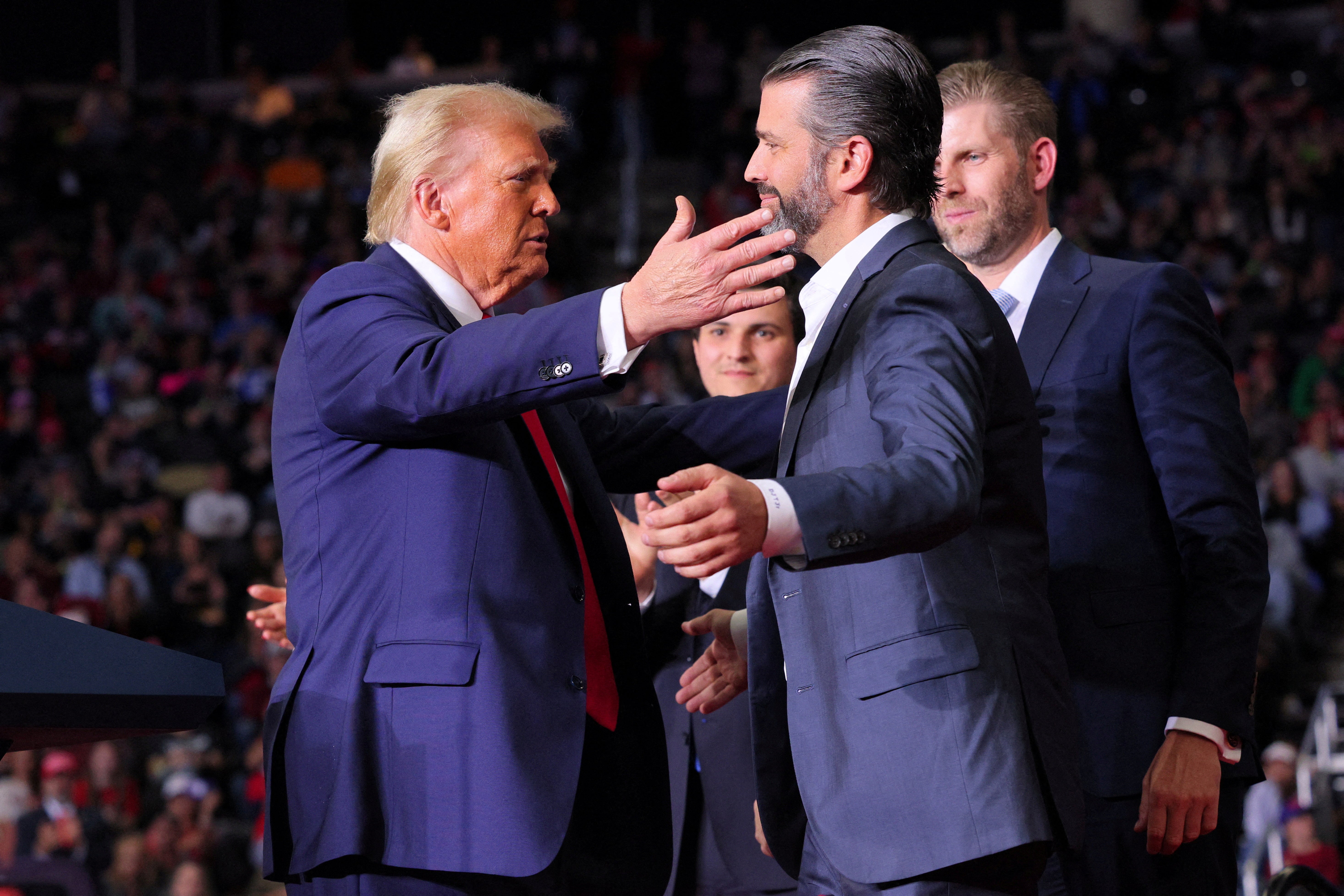 Donald Trump approaches to embrace Donald Trump Jr at a campaign rally