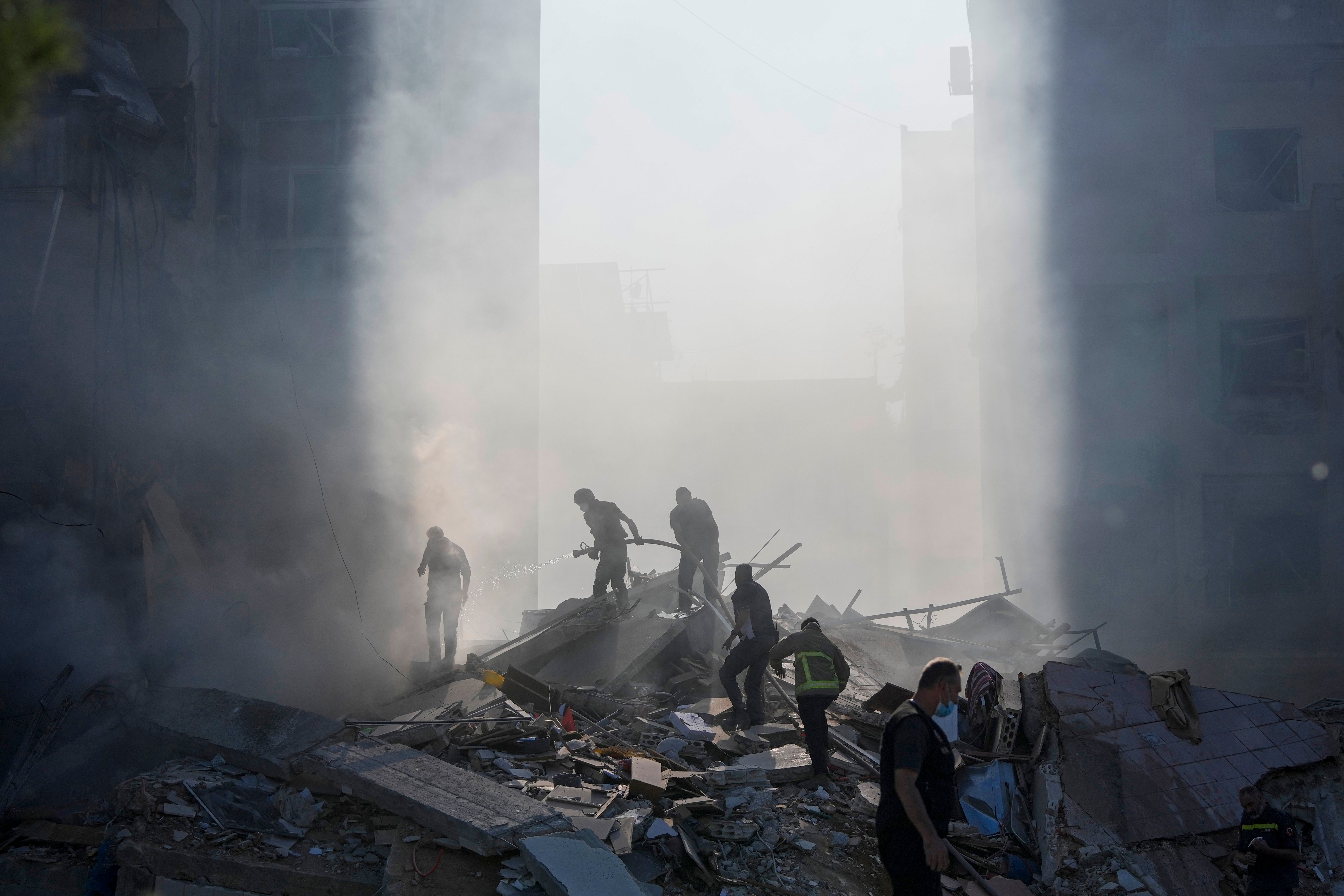 Civil defence workers extinguish a fire as smoke rises from the site of an Israeli airstrike in Tayouneh, Beirut, on Monday