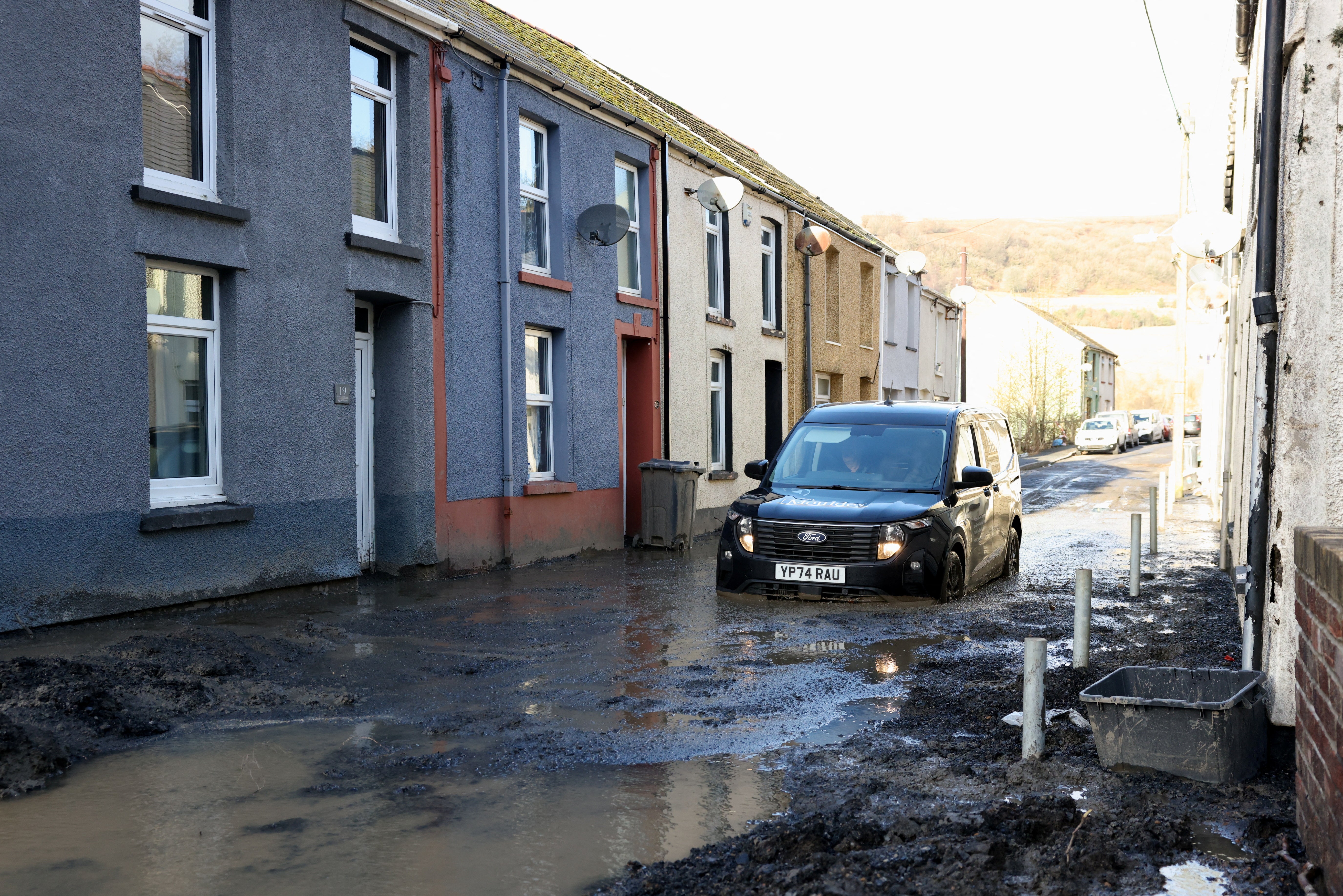 A car drives through mud at the site of a mudslide, in the aftermath of Storm Bert, in Cwmtillery