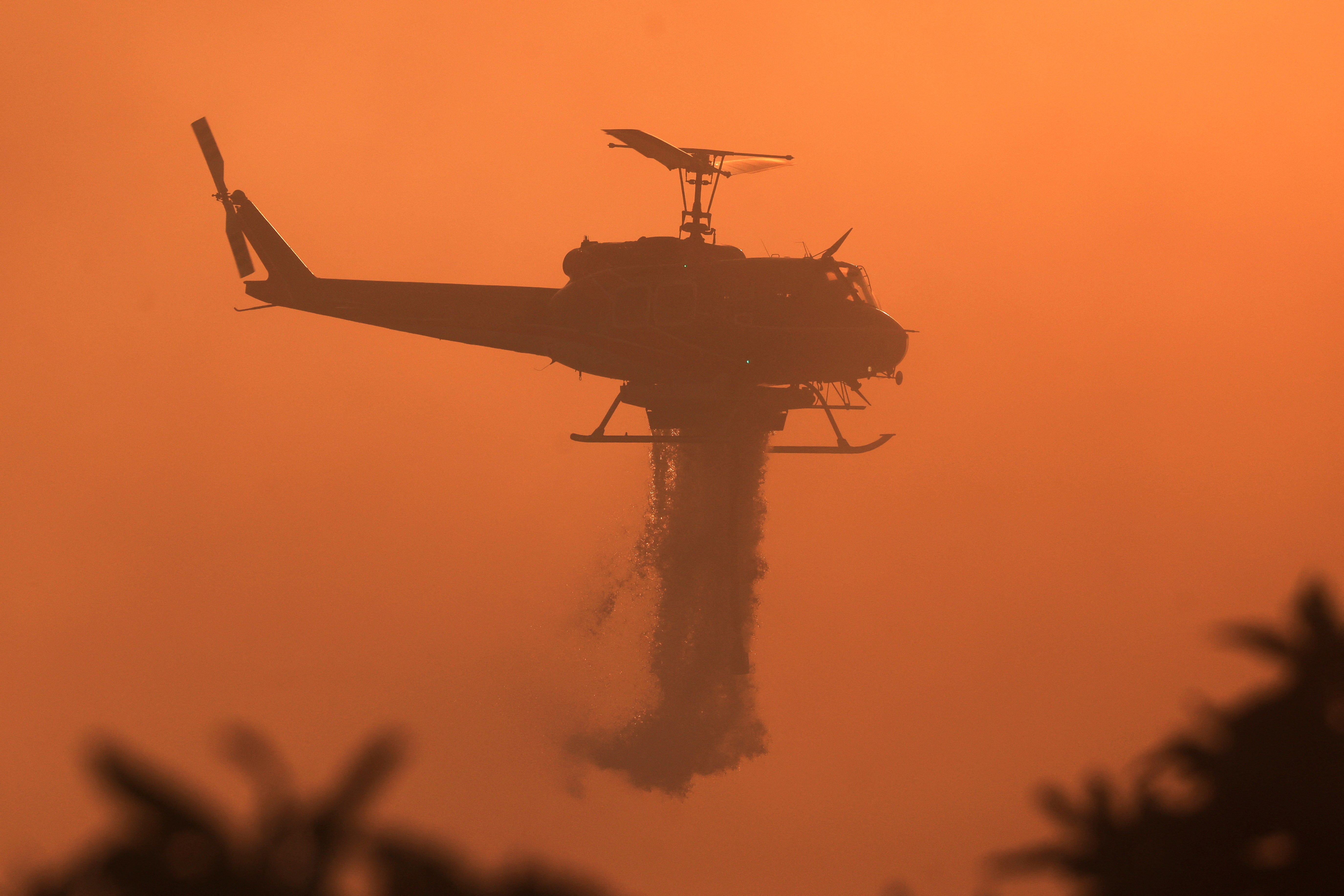 A firefighting helicopter drops water, as the Mountain Fire burns, in Santa Paula, California, this month. Fire weather has continued into November this year