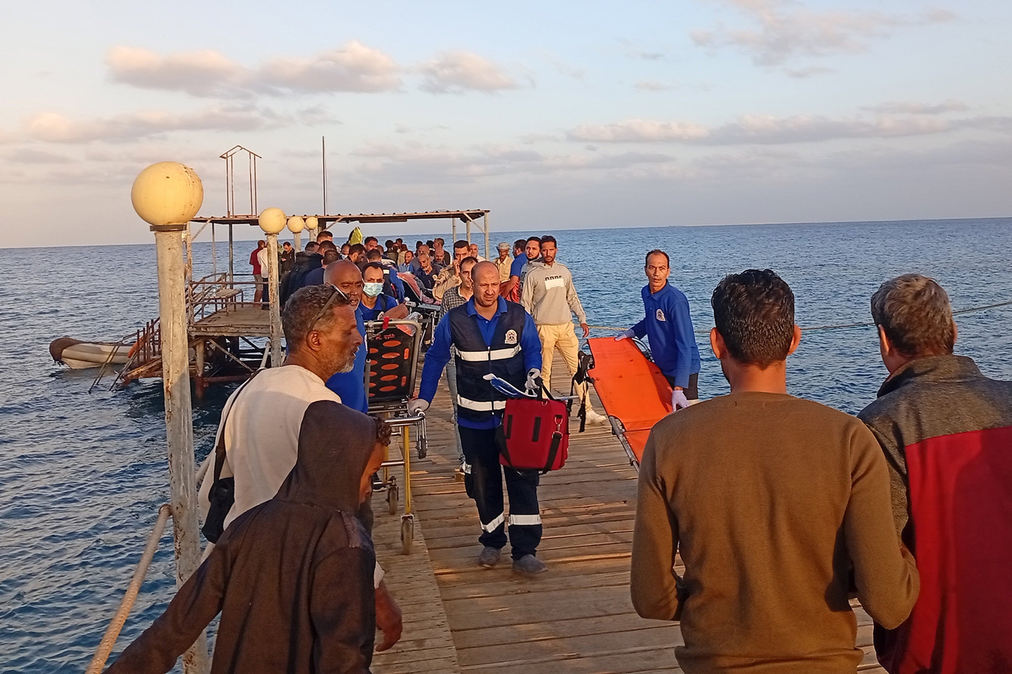 Medics and people wait for possible survivors after a boat sank at a harbour in Marsa Alam, Red Sea Governorate, in Egypt