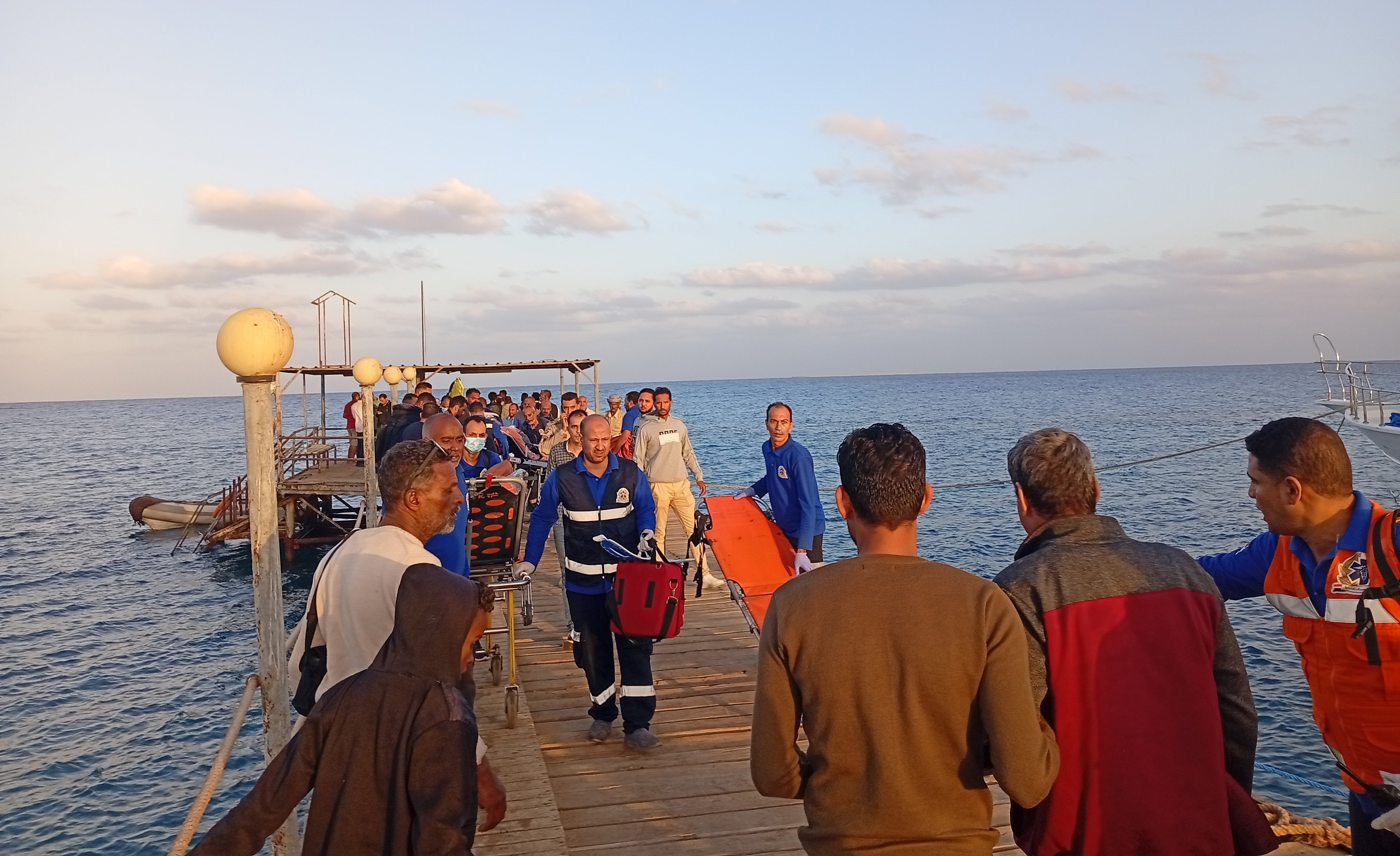 Medics and people wait for possible survivors after a boat sank at a harbour in Marsa Alam