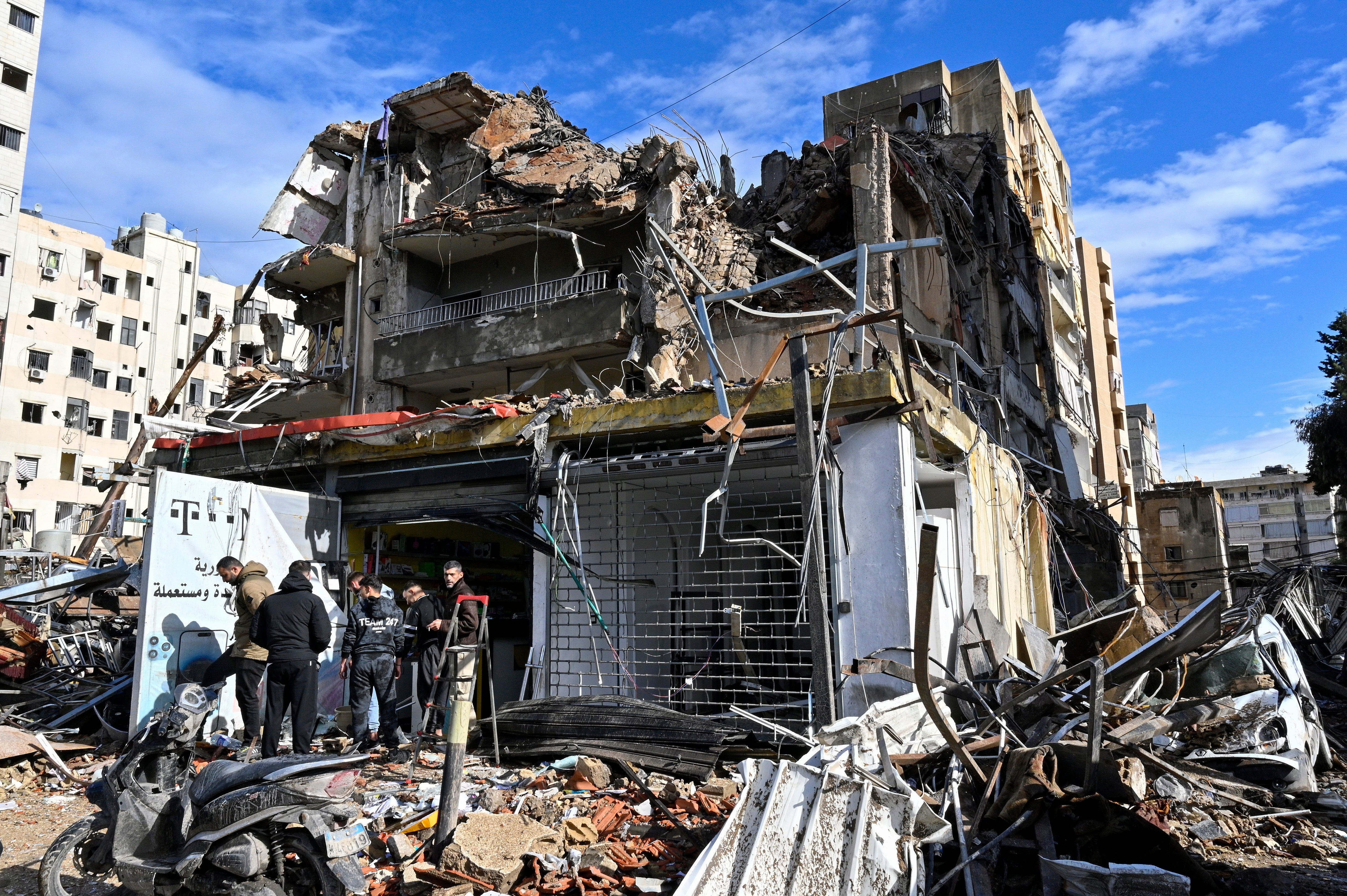 People stand next to a damaged building after an Israeli airstrike in the Al-Chiyah area in southern Beirut