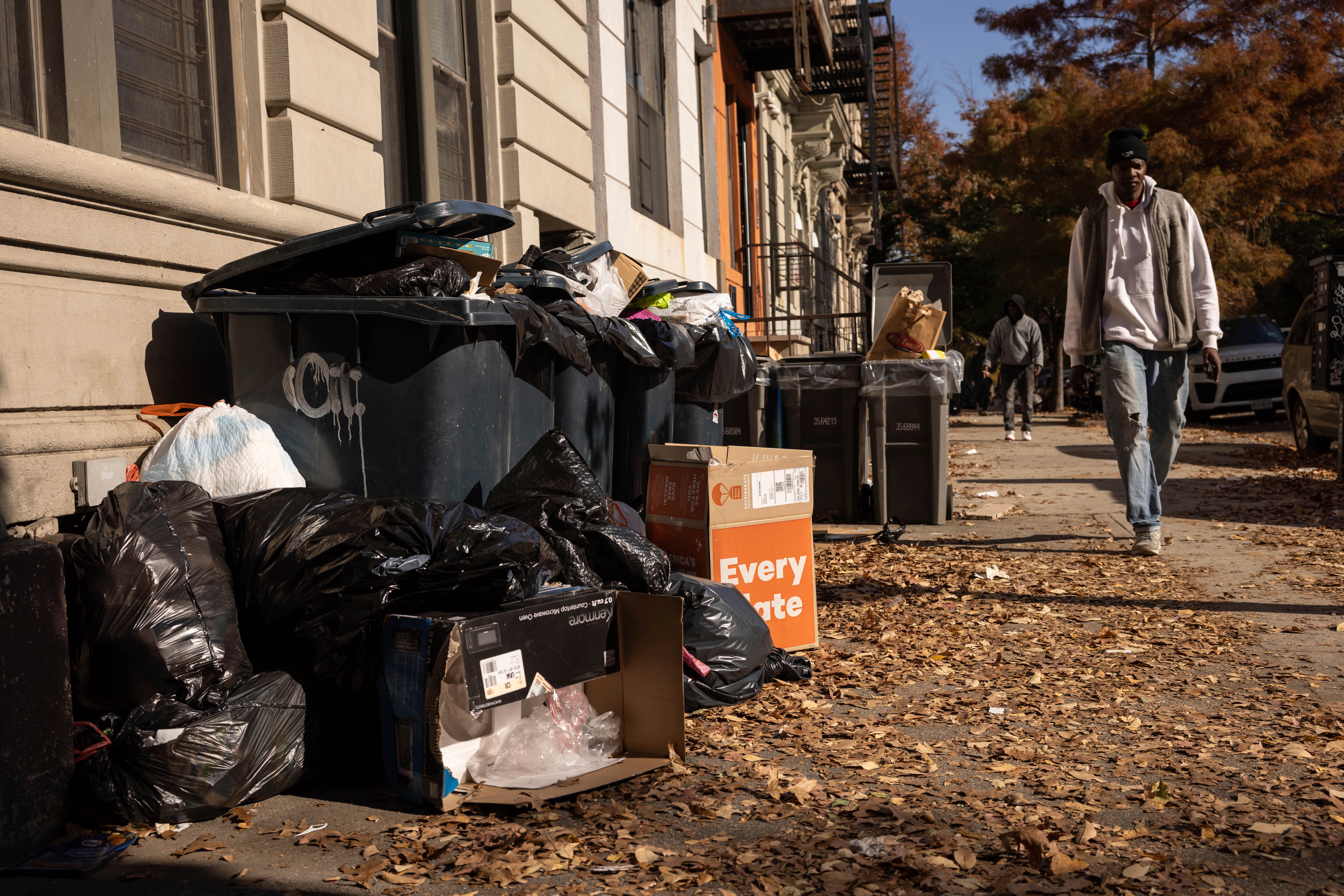 A person walks next to the pile of trash, Friday, Nov. 15, 2024, in the Brooklyn borough of New York