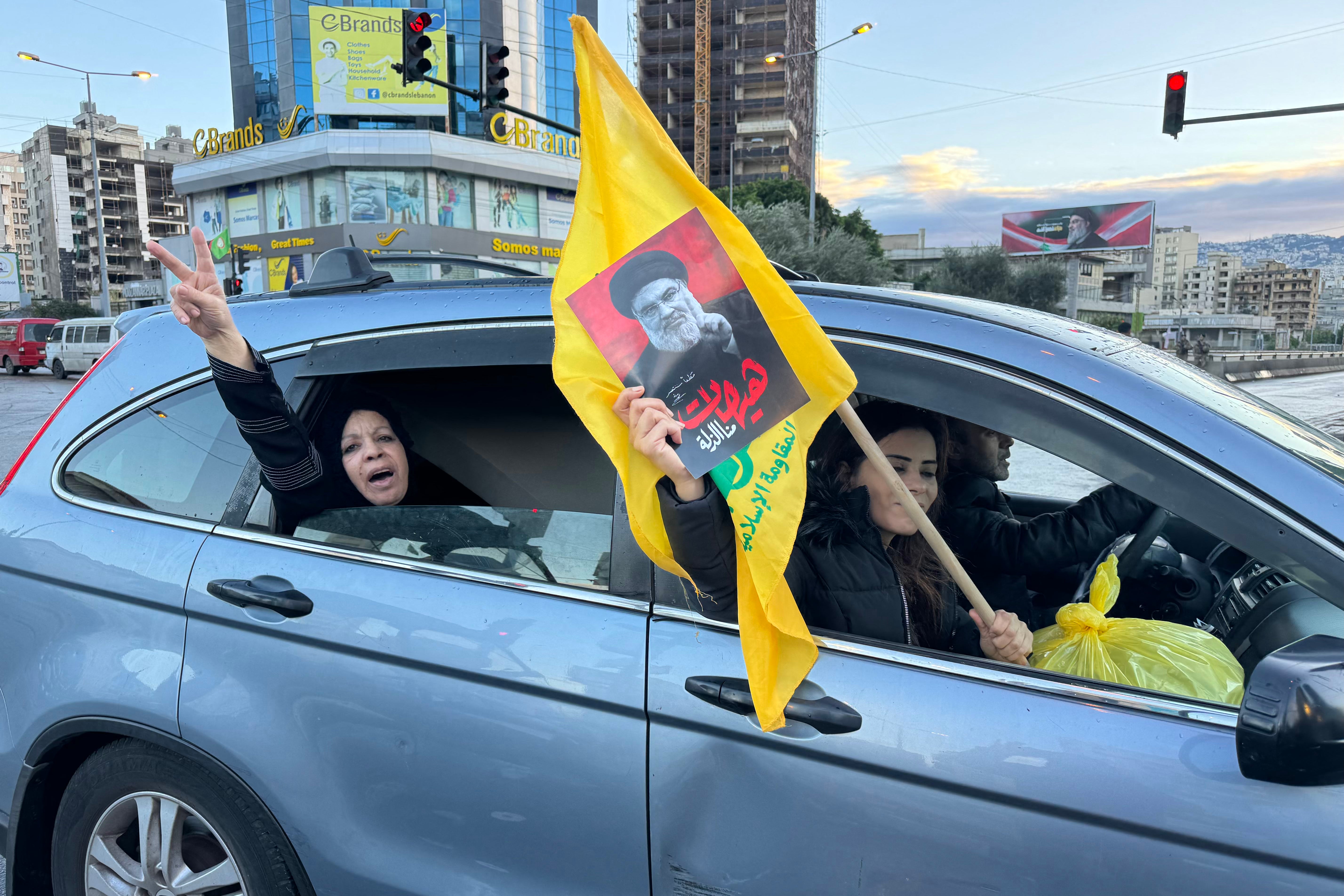 Motorists wave the flag of Hezbollah and the portrait of slain Hezbollah leader Hasan Nasrallah as they parade in Beirut's southern suburb