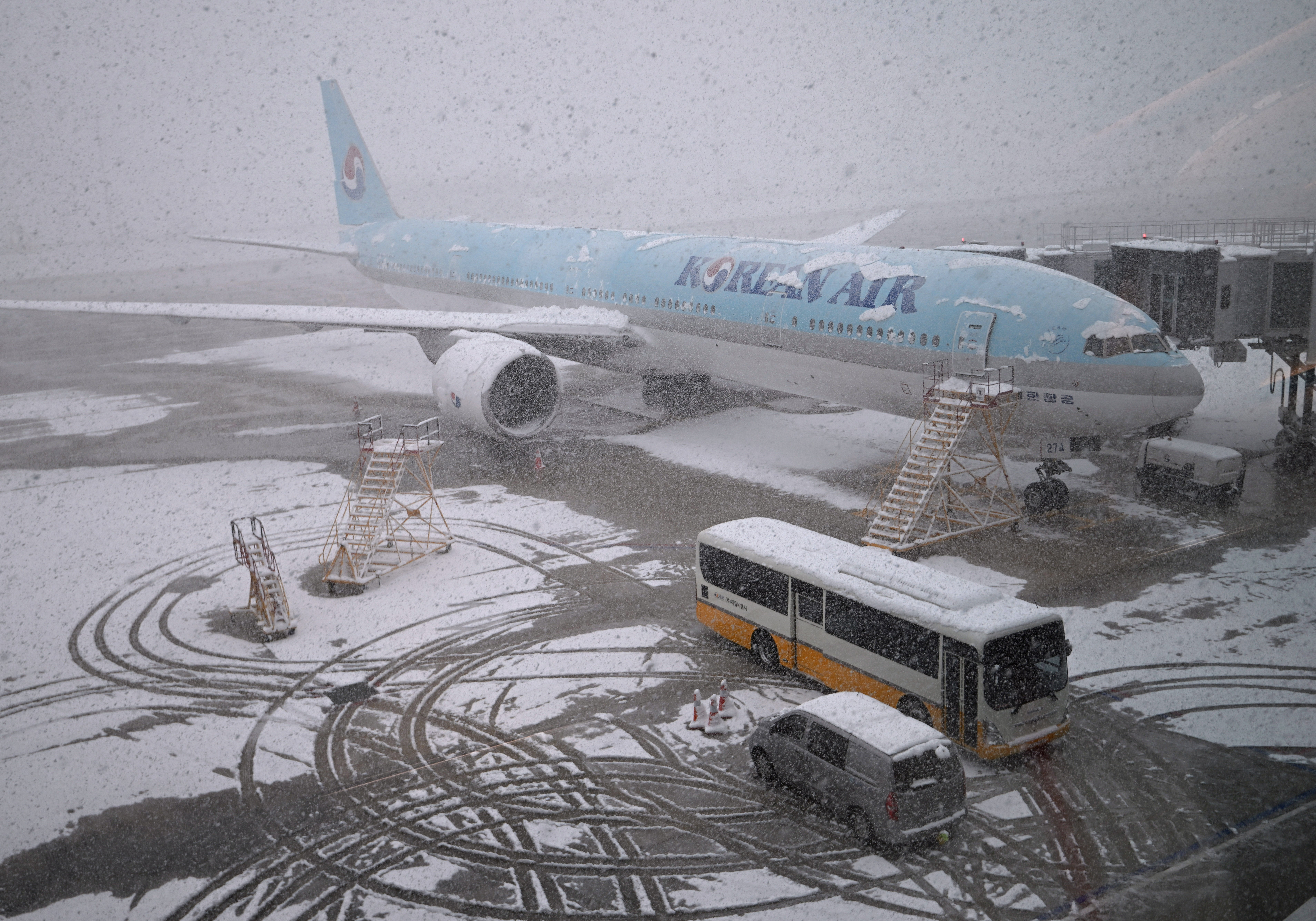 A Korean Air plane is parked on the tarmac during snowfall as seen through a window at Incheon international airport