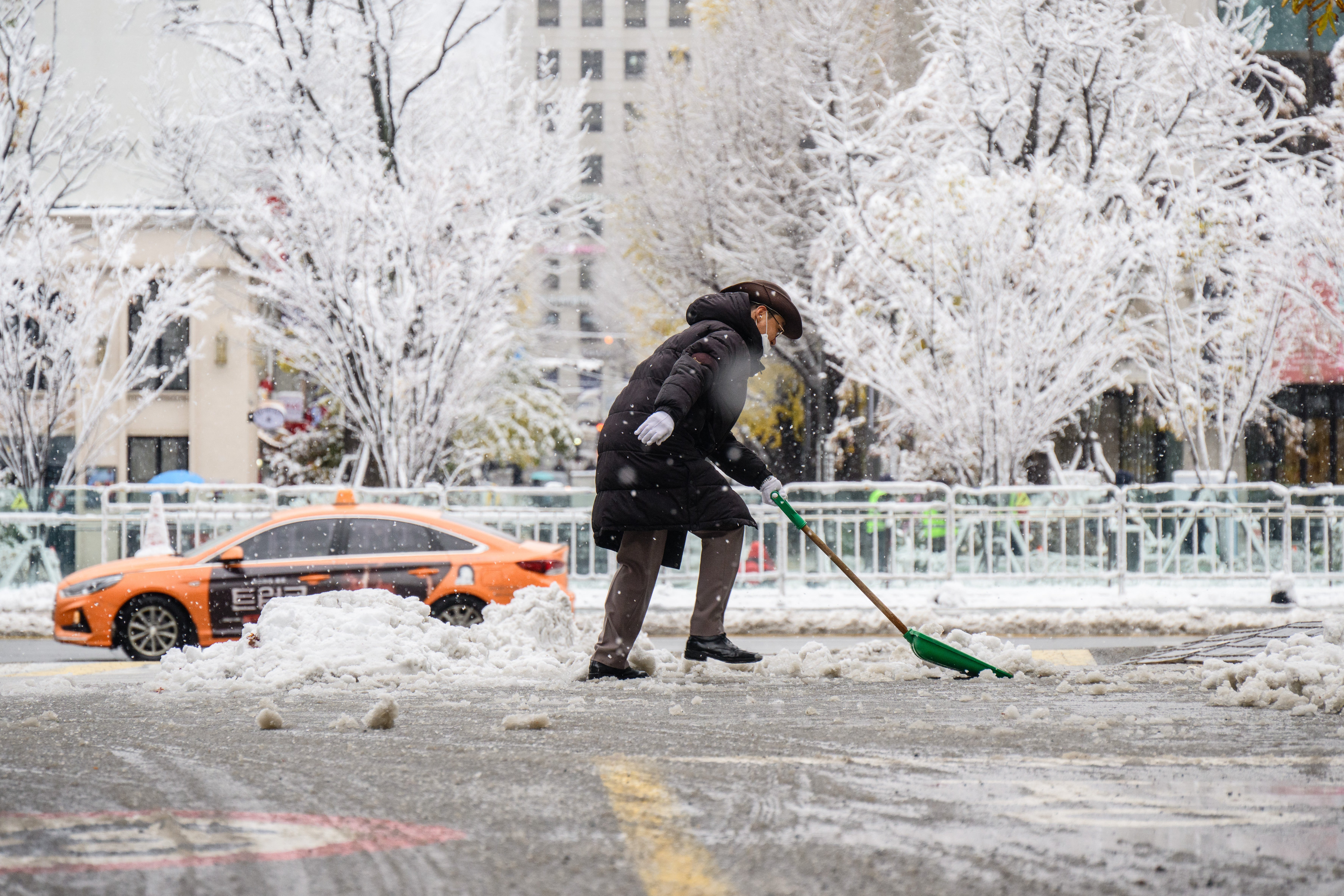 A car park attendant clears a road of snow and slush