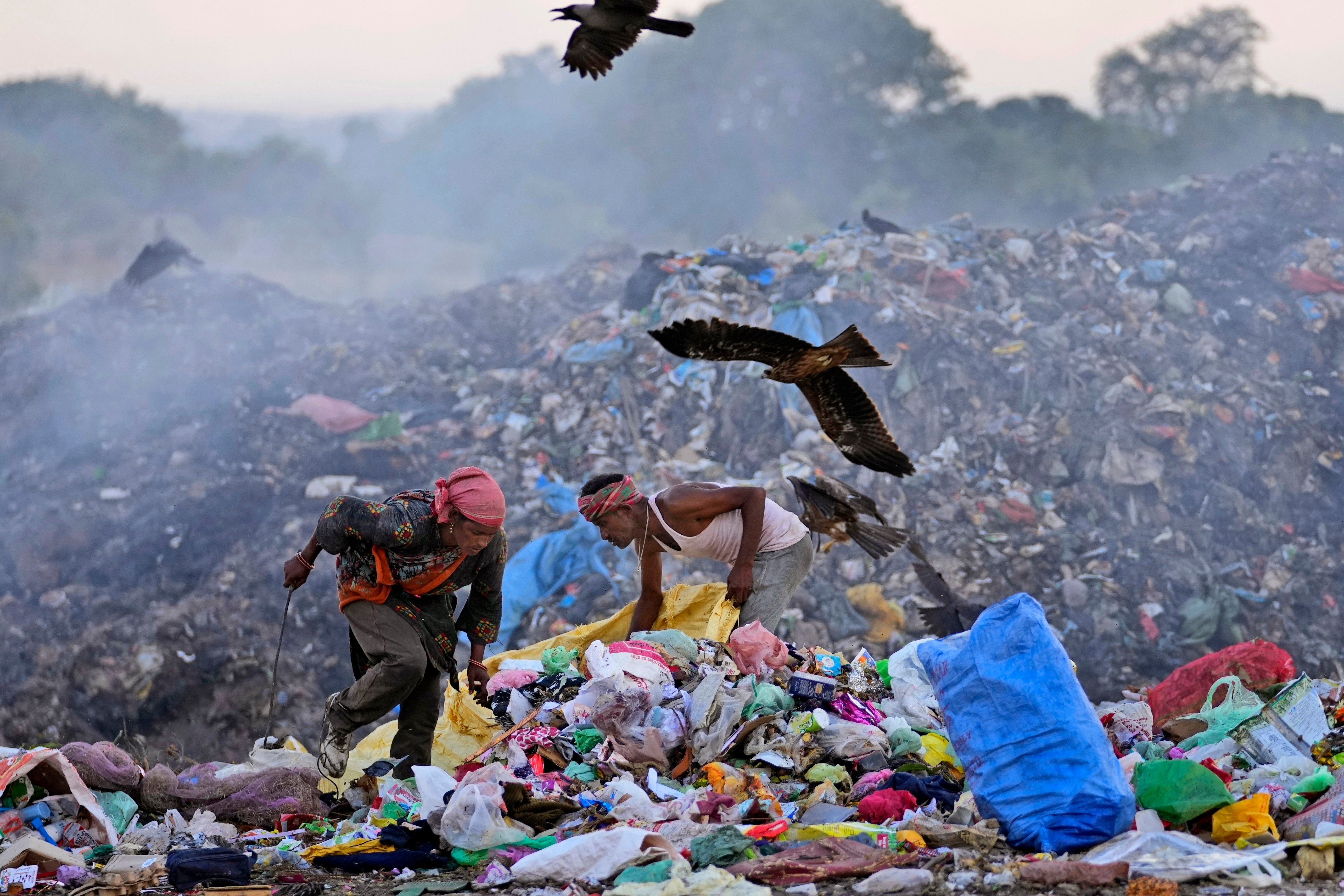 FILE- Waste pickers Salmaa and Usmaan Shekh, right, search for recyclable materials during a heat wave at a garbage dump on the outskirts of Jammu, India