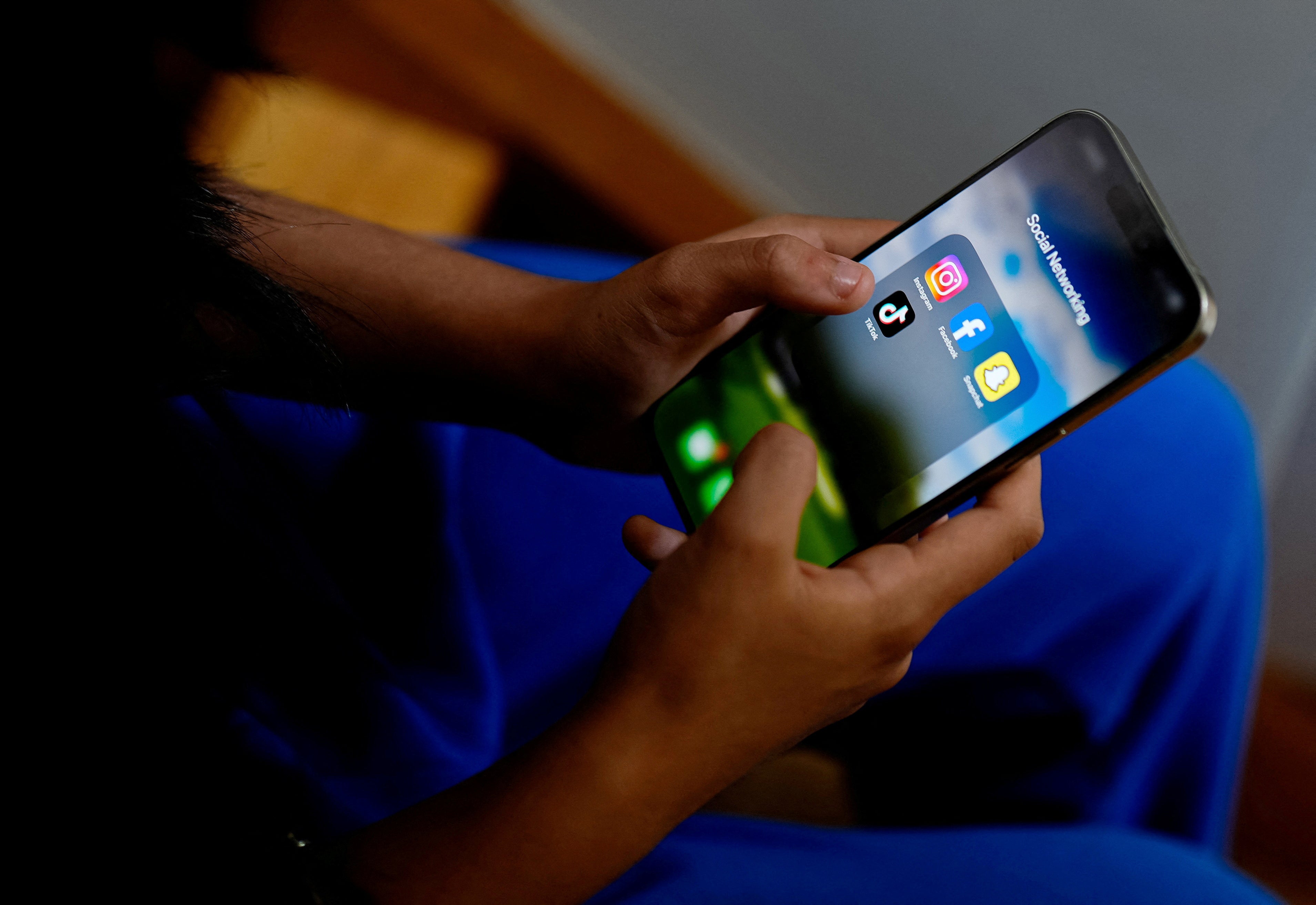 A student poses with her mobile showing her social media applications in Melbourne