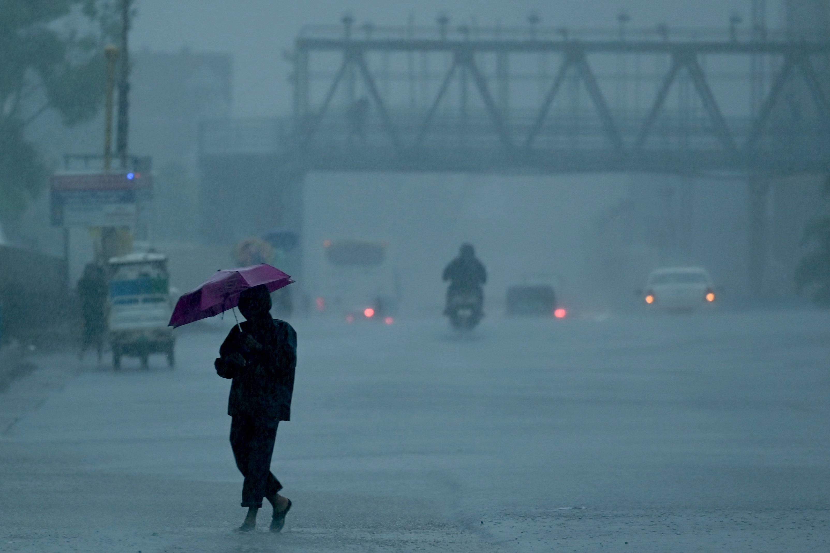 People commute along a street amid heavy rains ahead of a cyclonic storm in Chennai