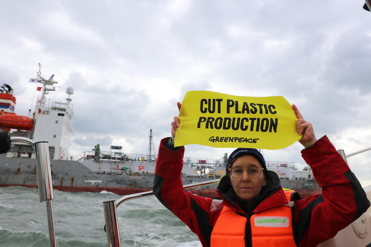 An activist holds a banner calling for cut in plastic production at the UN plastics talks