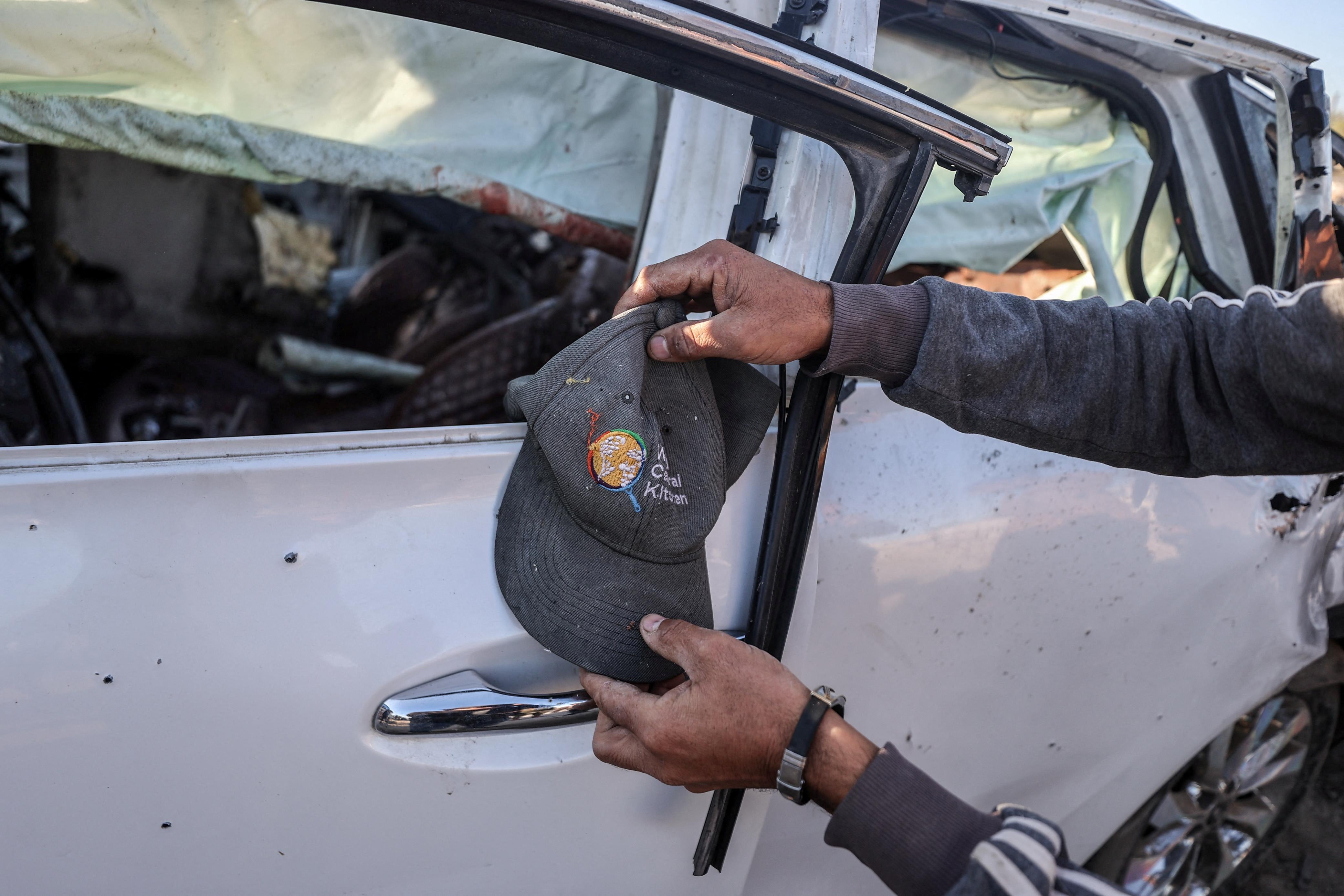 A person holds a cap next to a vehicle in which employees of the World Central Kitchen (WCK) were reportedly killed in an Israeli strike