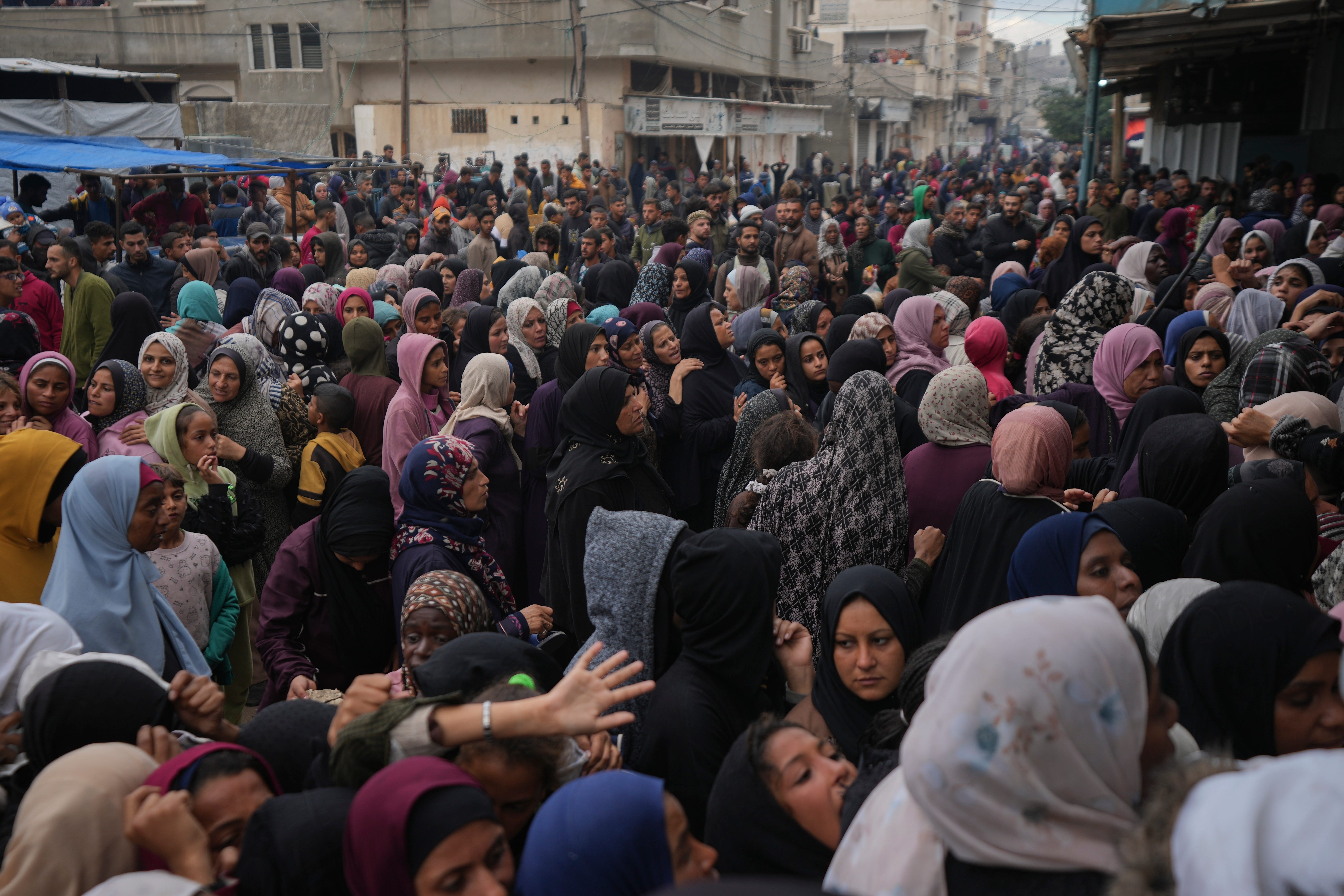 Palestinians gather for food at a distribution centre (Abdel Kareem Hana/AP)