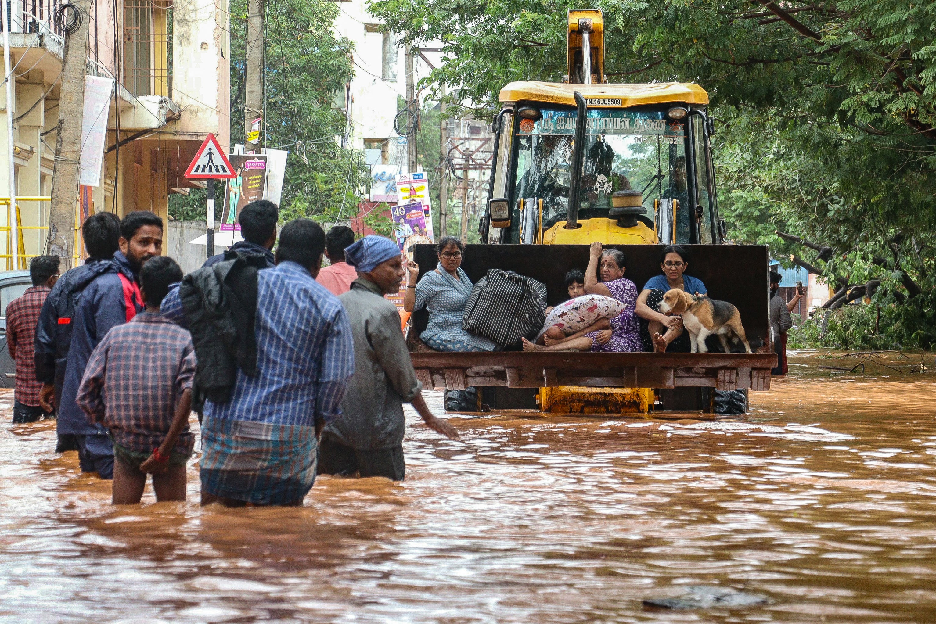 People move through a flooded street after heavy rainfall in Puducherry on 1 December 2024